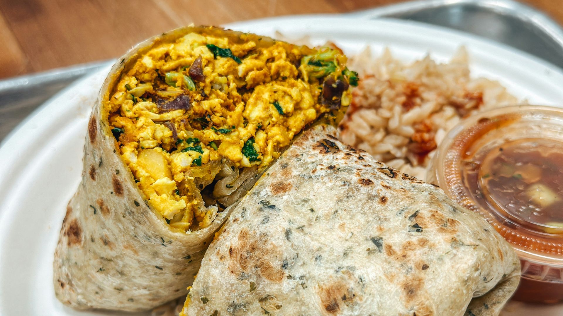a white plate topped with a burrito and rice
