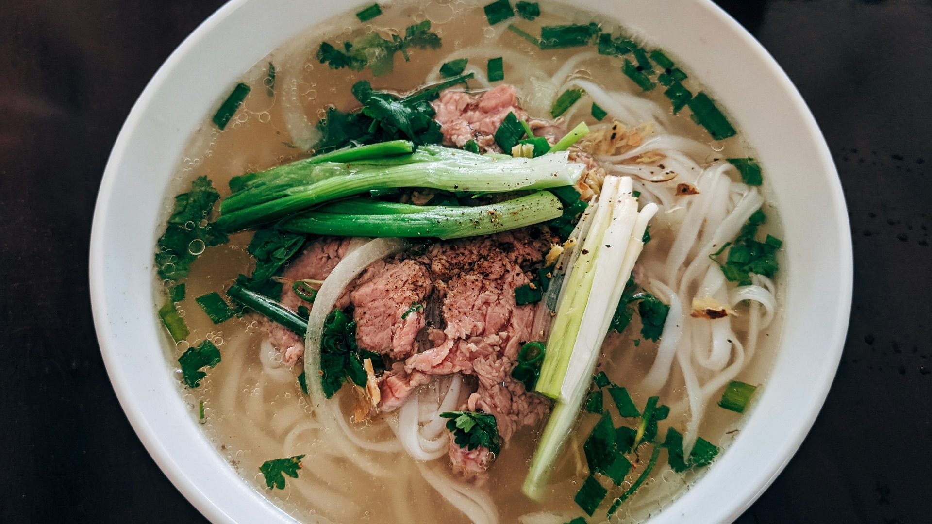 white noodle soup with green leaf vegetable in white ceramic bowl