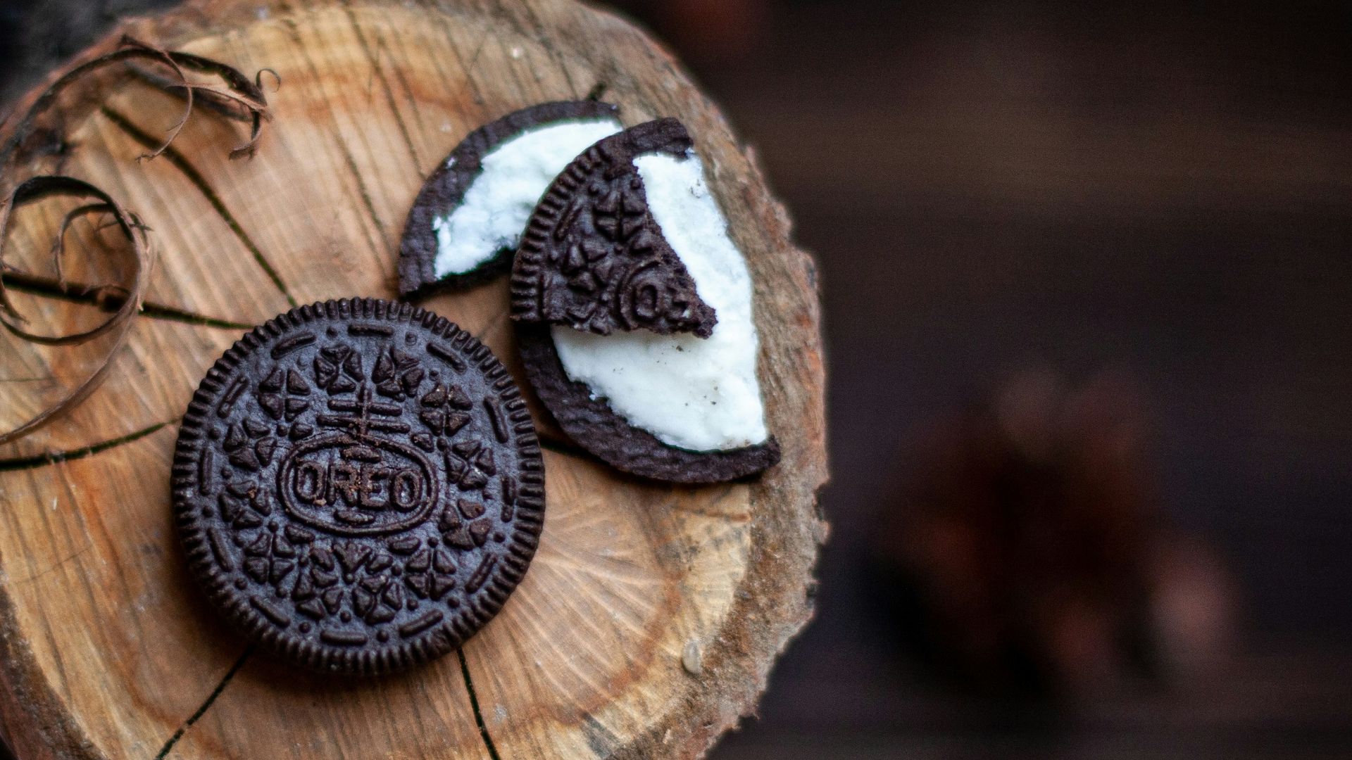 Two chocolate sandwich cookies with cream filling on wood.