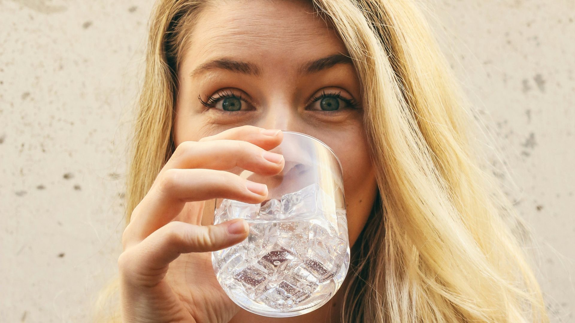 woman in white crew neck shirt drinking water