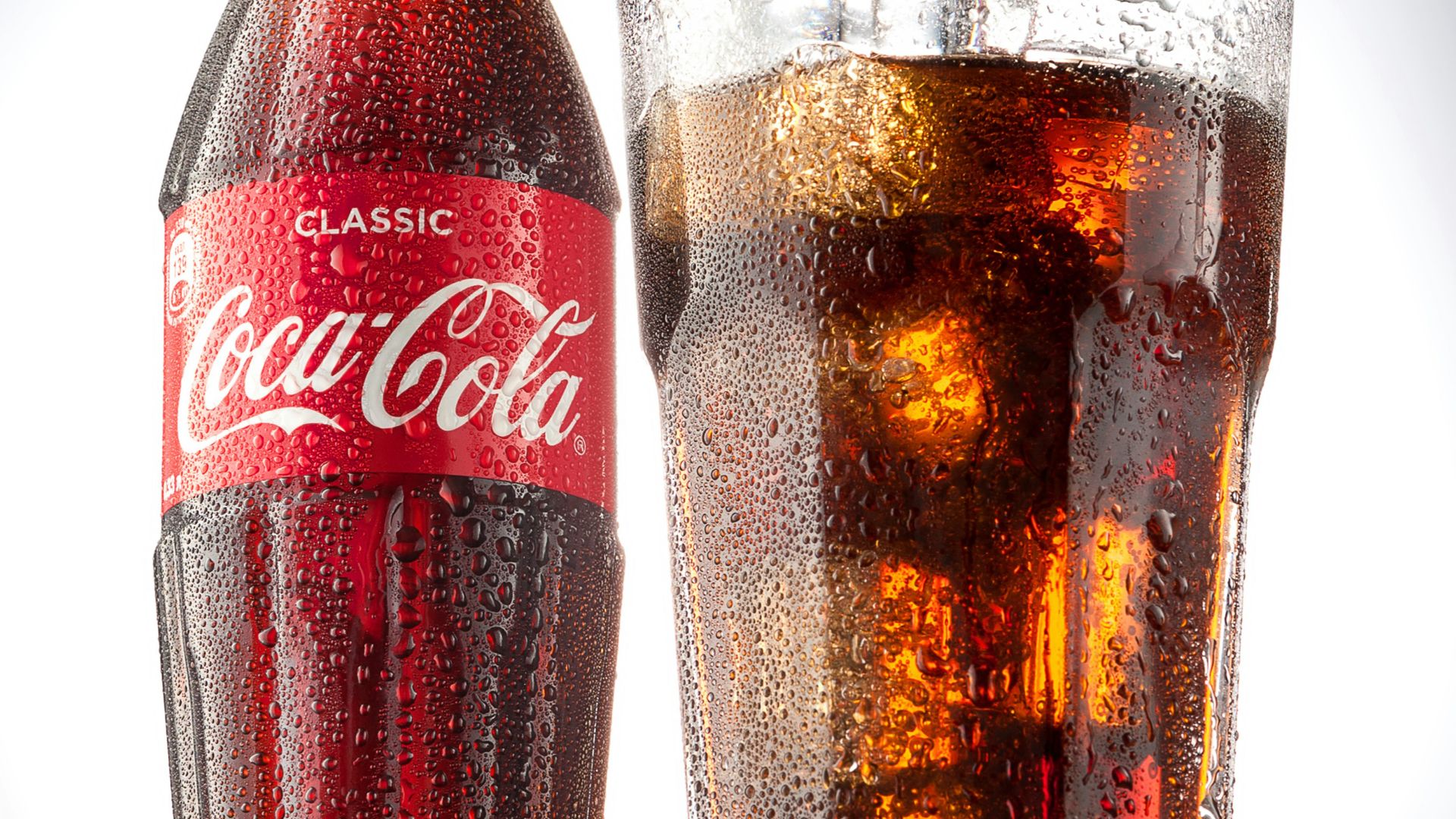 coca cola bottle beside drinking glass