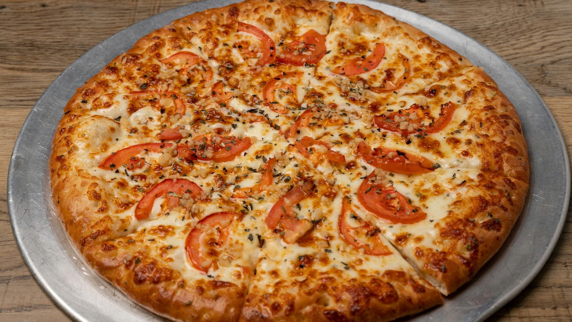 A pizza sitting on top of a pizza pan on top of a wooden table