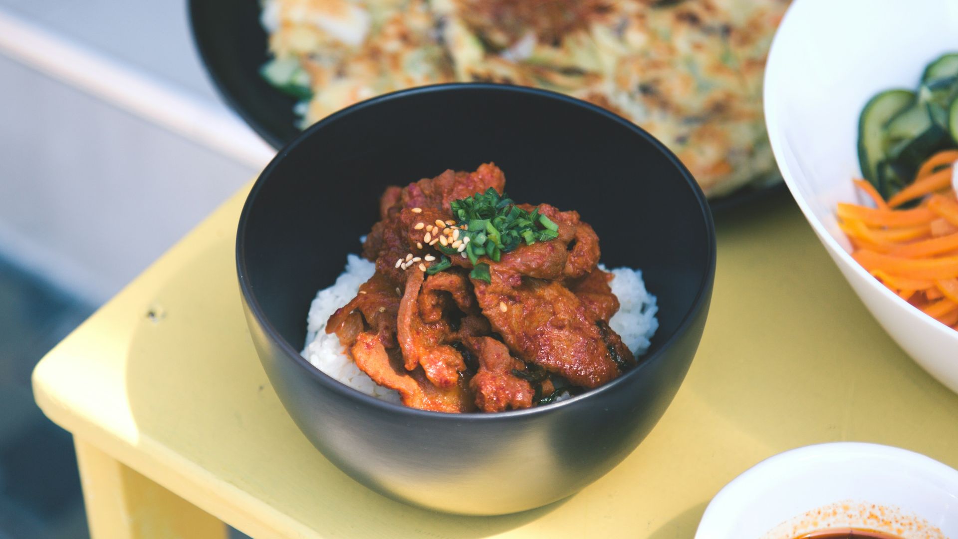a yellow table topped with bowls of food