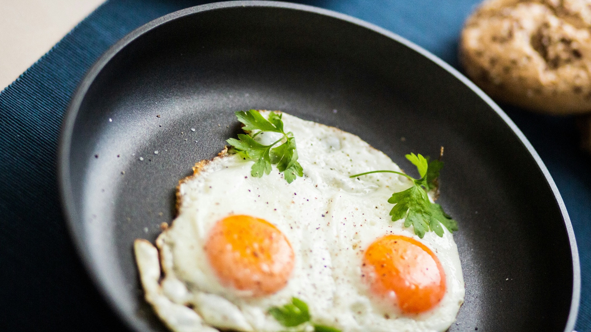 two fried eggs in a frying pan next to a plate of cookies