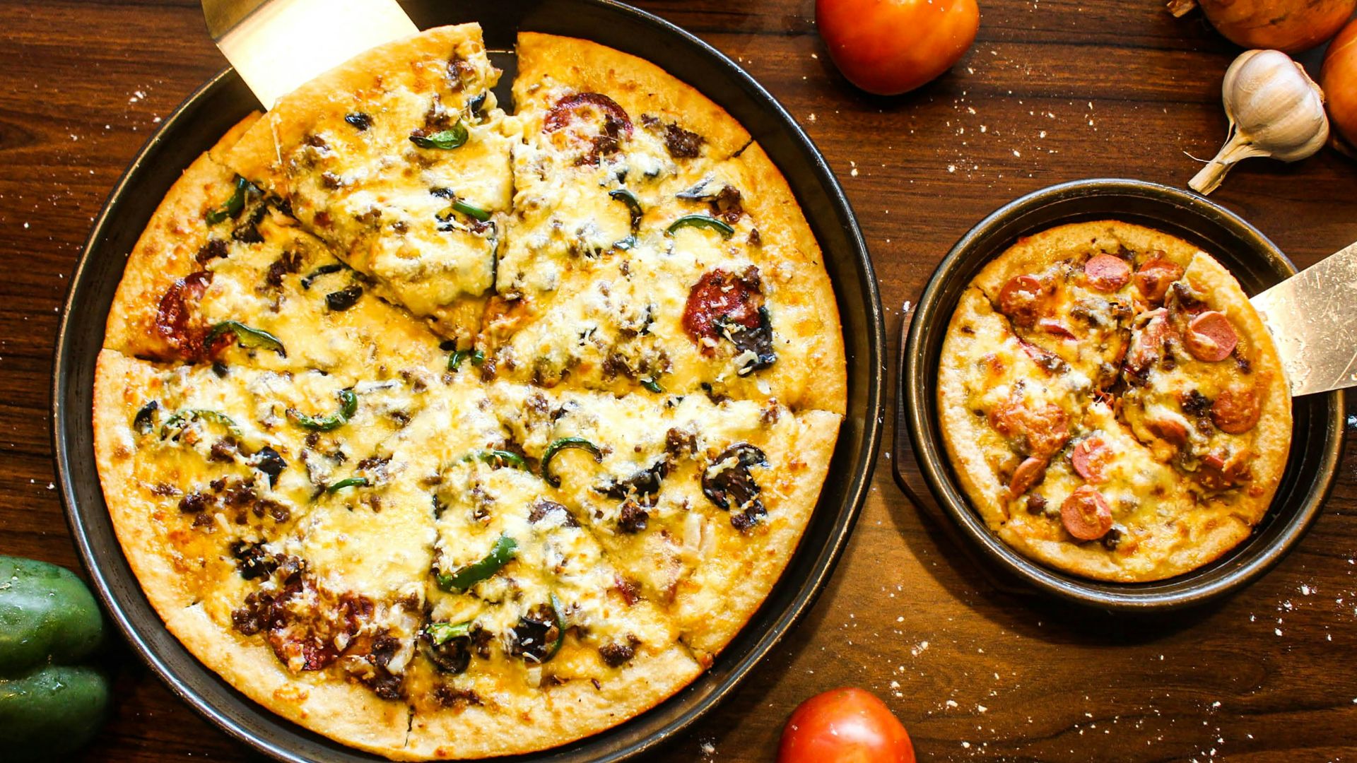 a pizza sitting on top of a pan on top of a wooden table