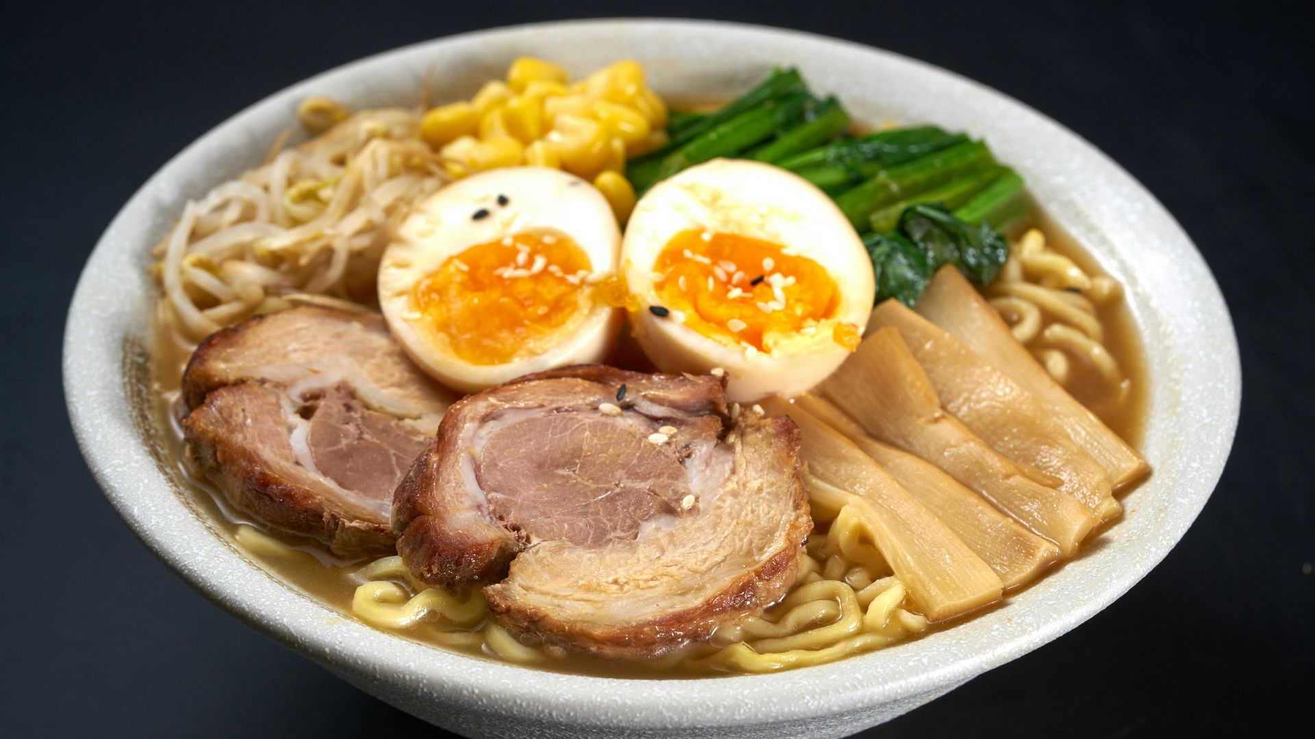 a bowl of ramen with meat, eggs, noodles and vegetables