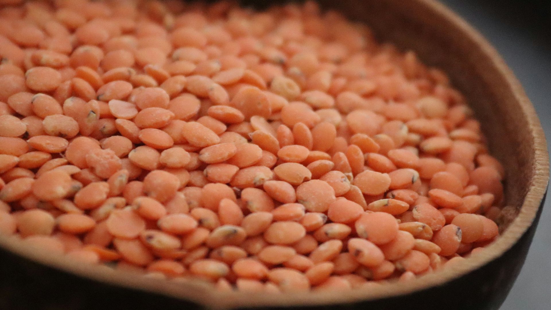 A wooden bowl filled with red beans on top of a table