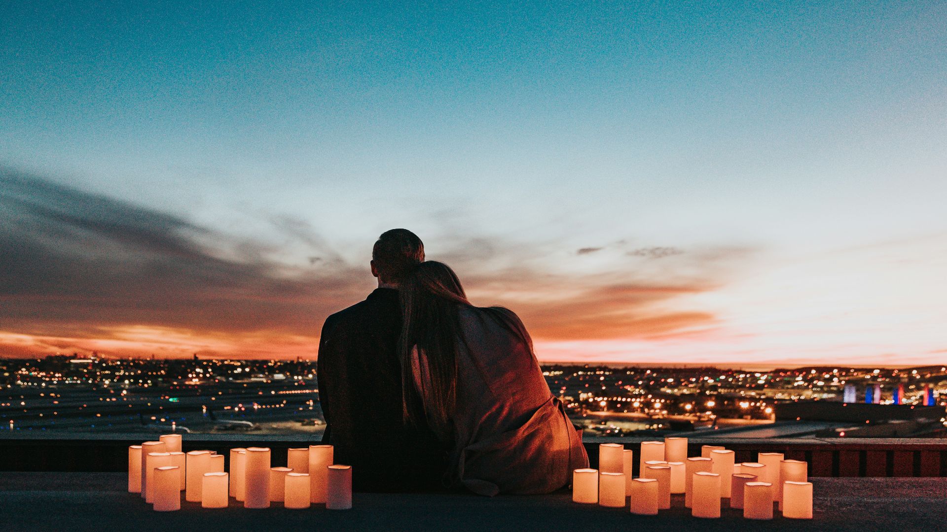 couple sitting on the field facing the city