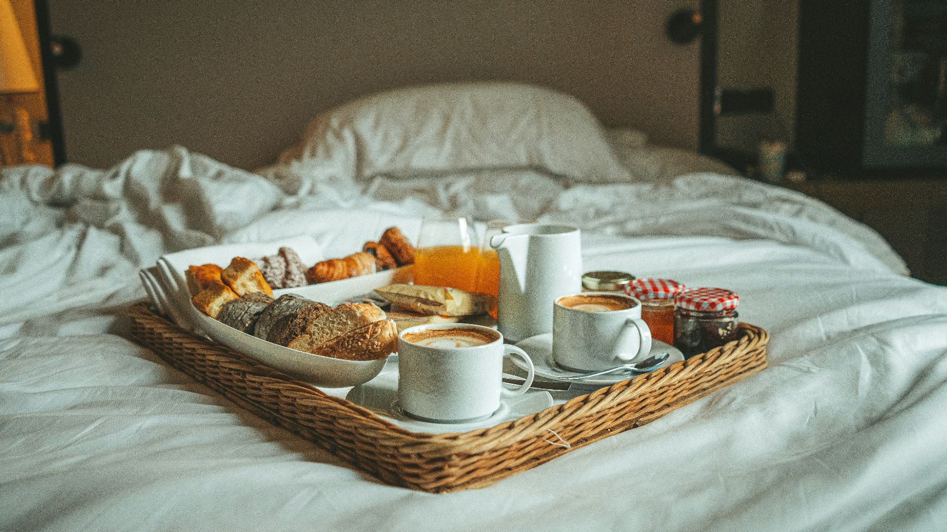 a tray of breakfast on a bed with white sheets