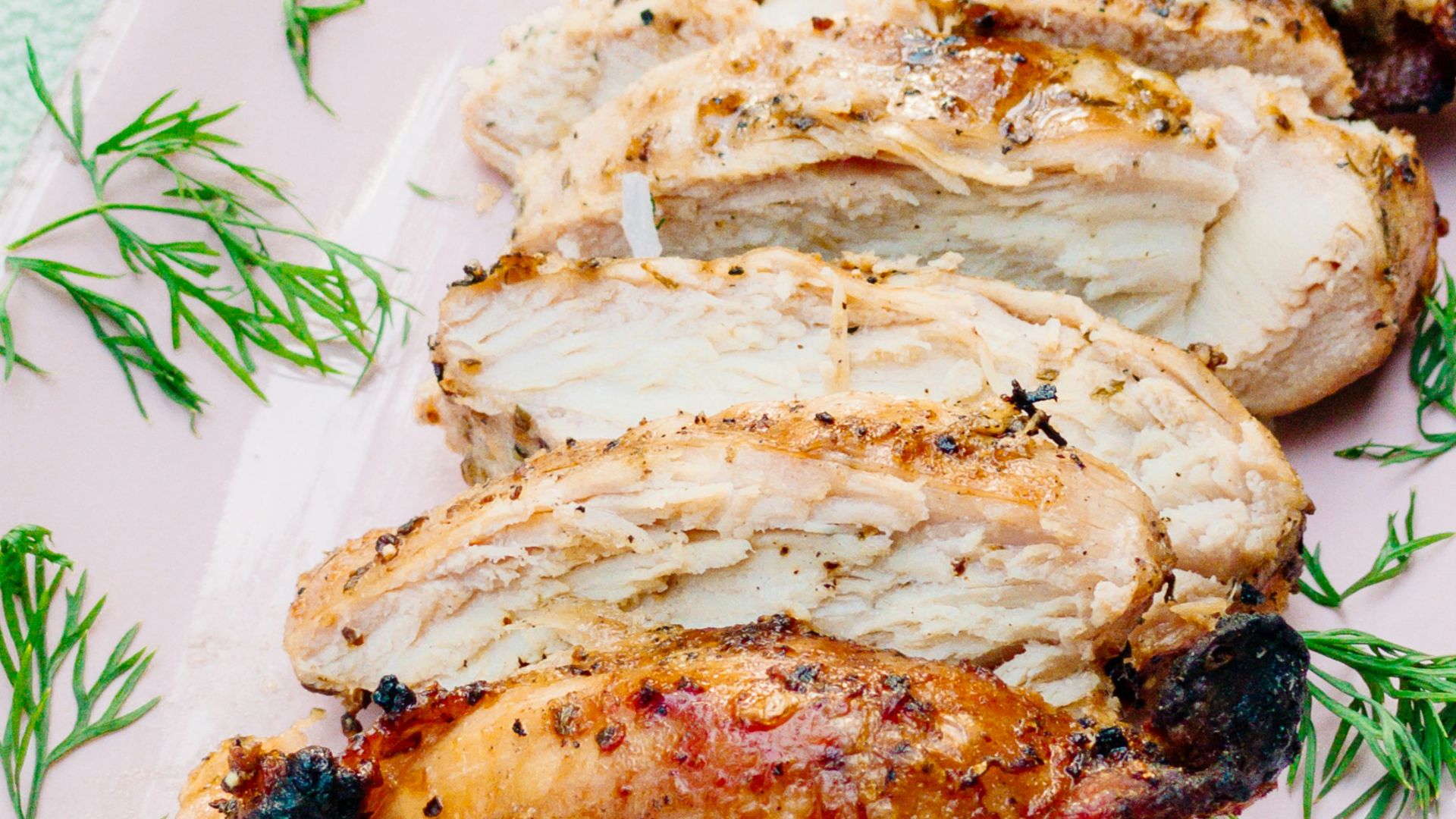 a pink plate topped with meat covered in sauce