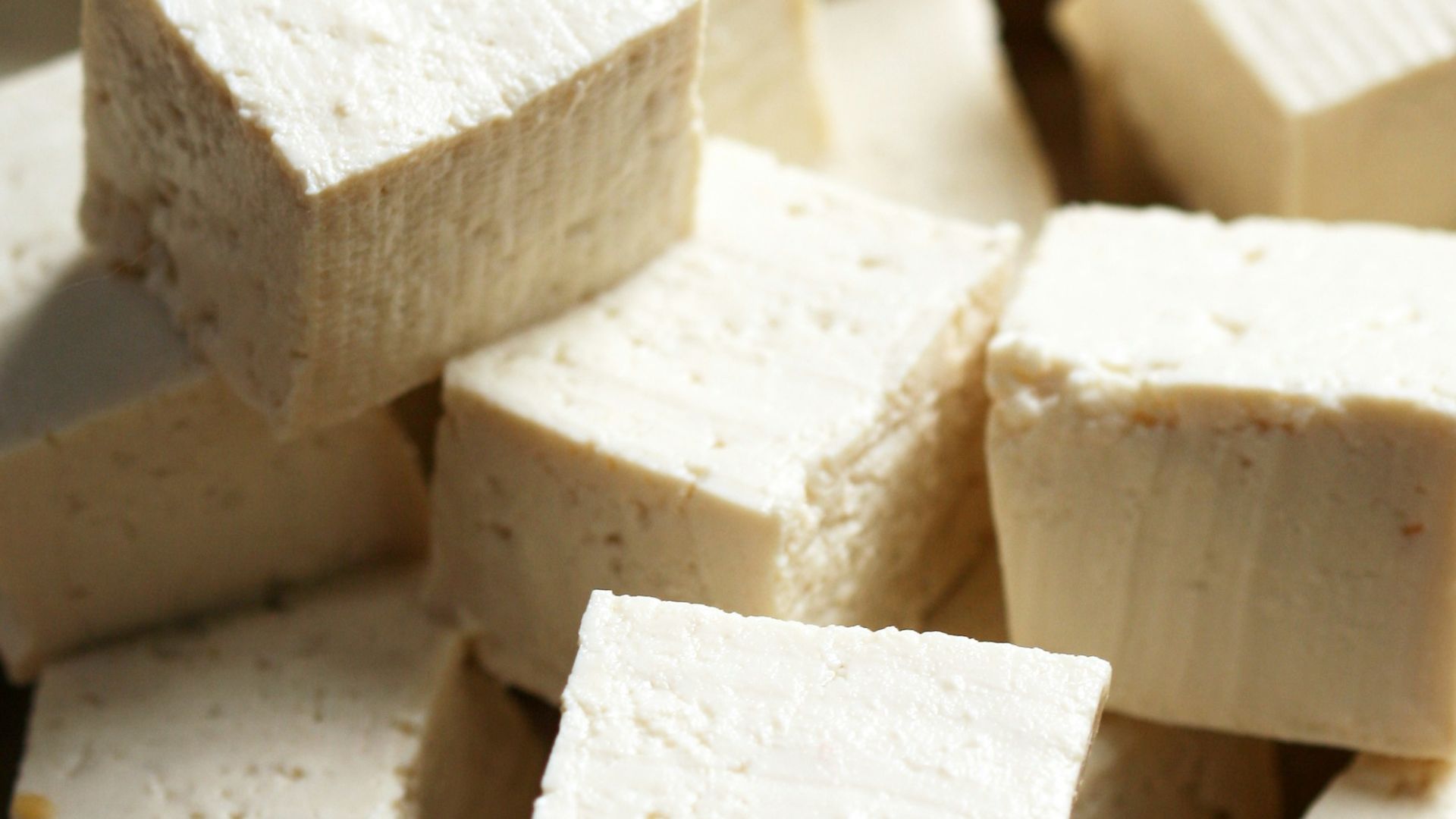 A pile of tofu cubes sitting on top of a cutting board