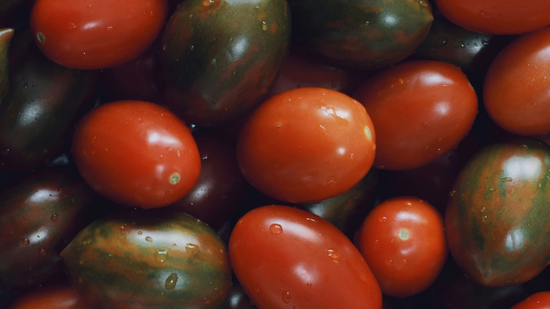 A pile of tomatoes and avocados sitting next to each other