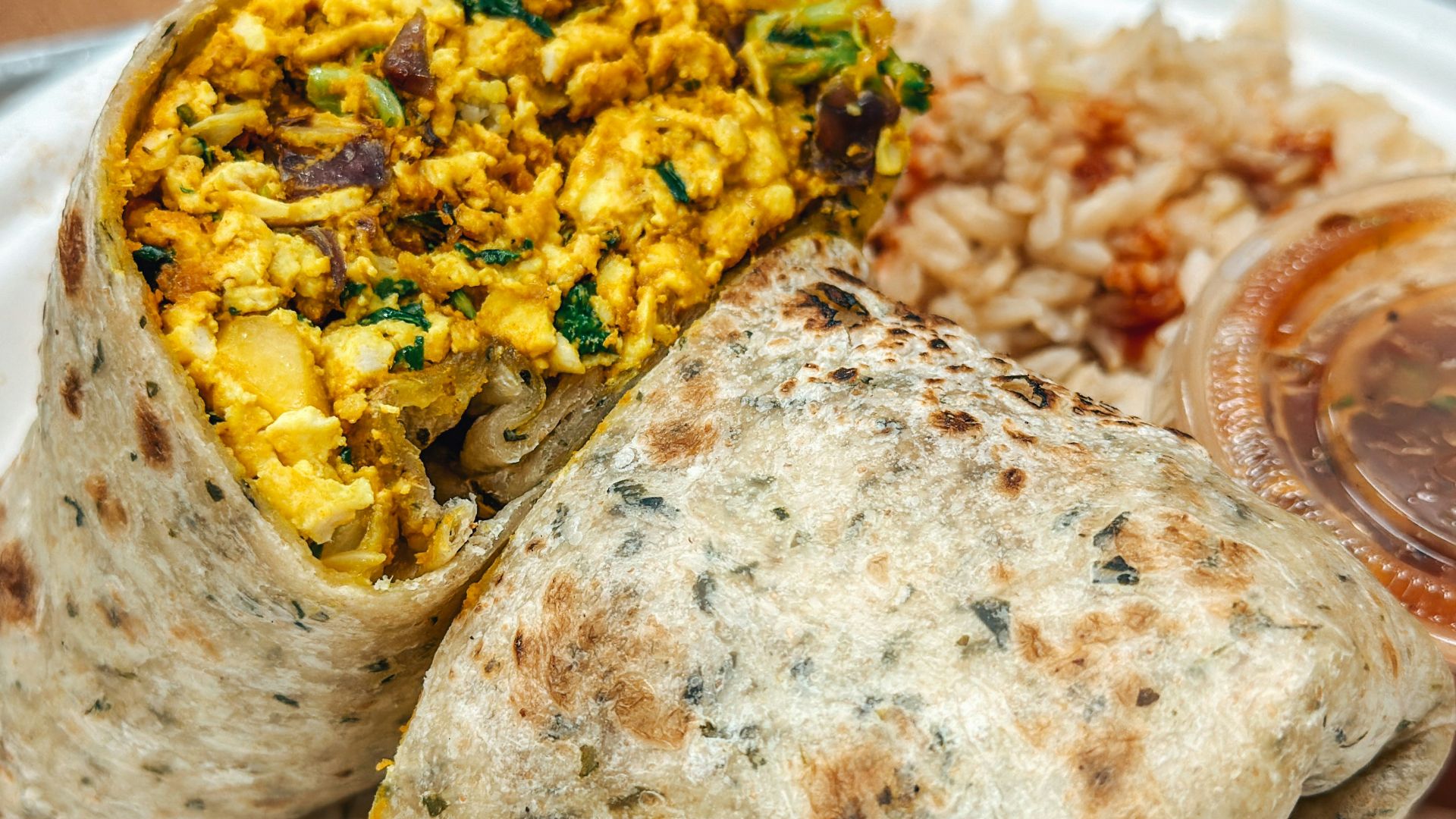 a white plate topped with a burrito and rice
