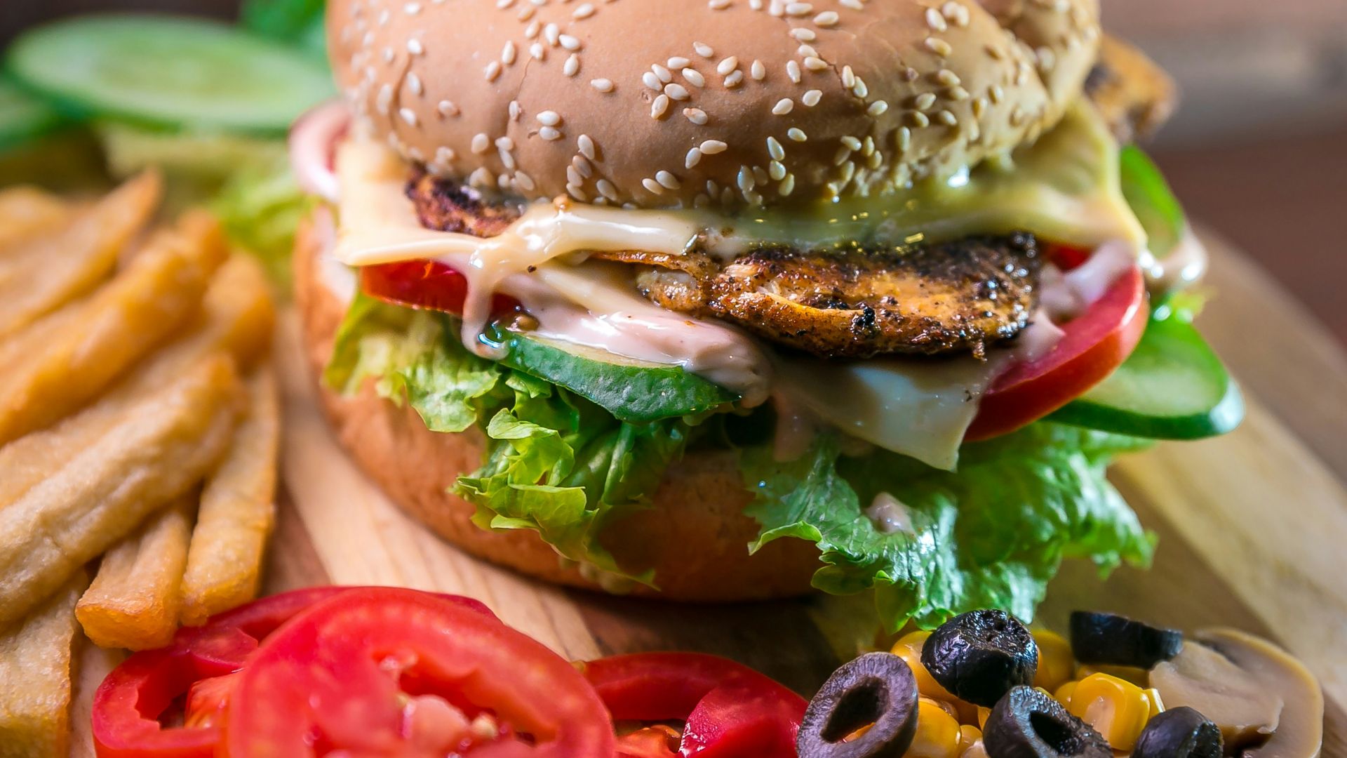 hamburger with vegetables and meat beside French fries