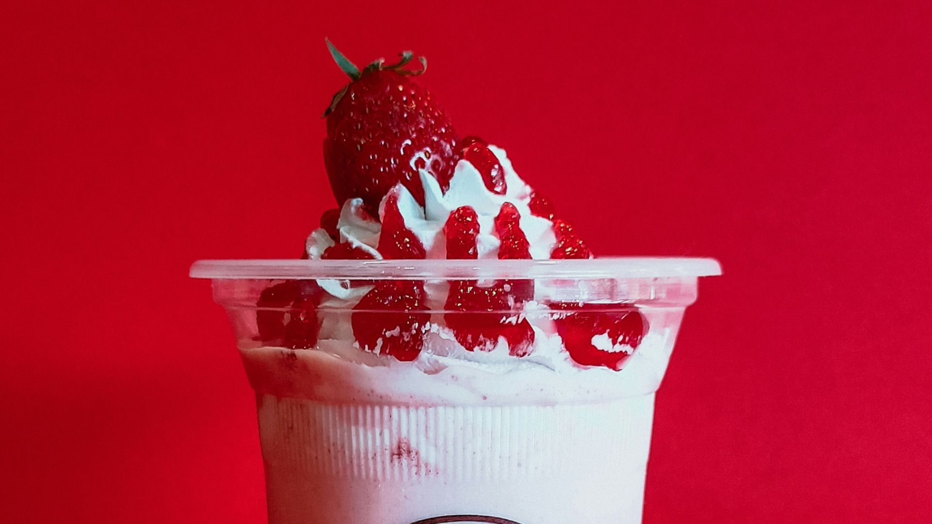 a cup of ice cream with strawberries on a red background
