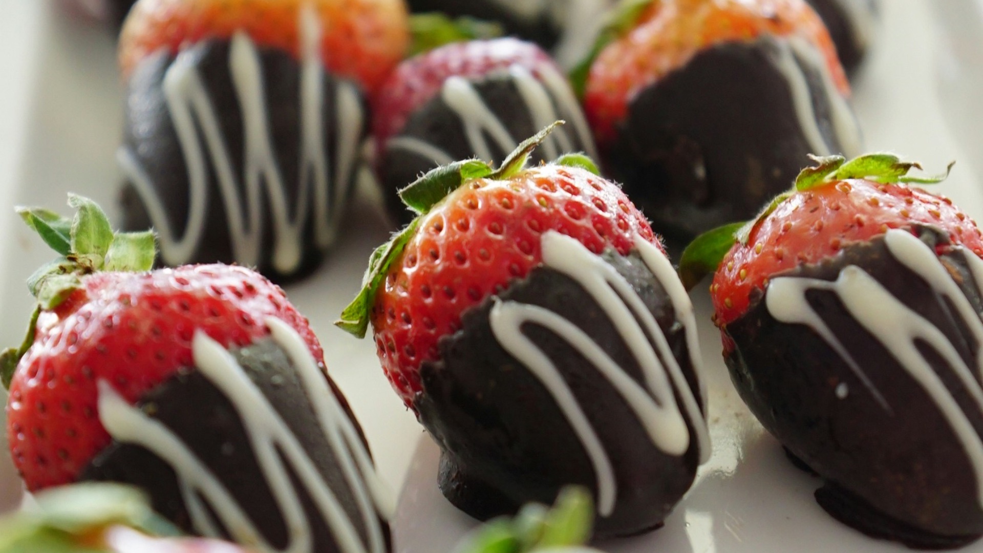 a plate of chocolate covered strawberries on a table