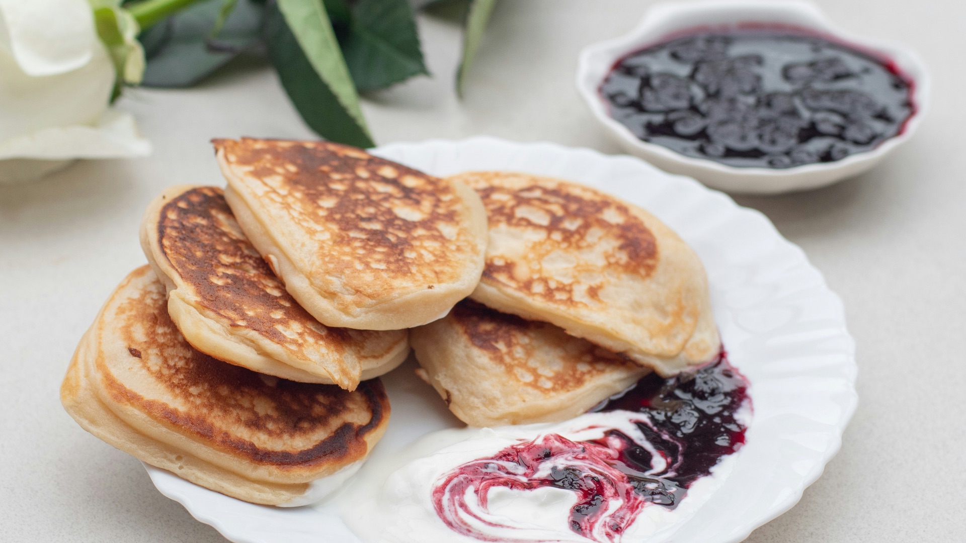 a white plate topped with pancakes next to a bowl of blueberries