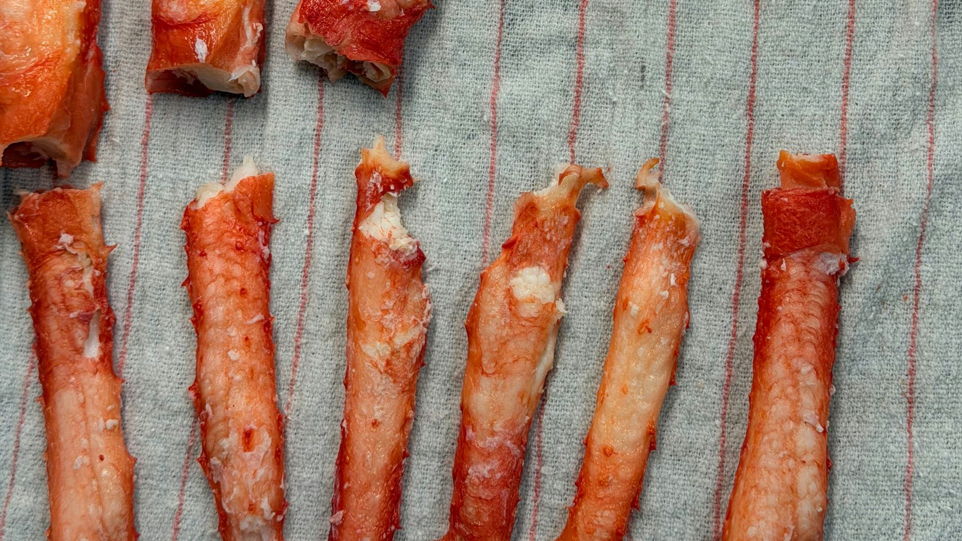 Cooked crab legs arranged on a striped cloth.