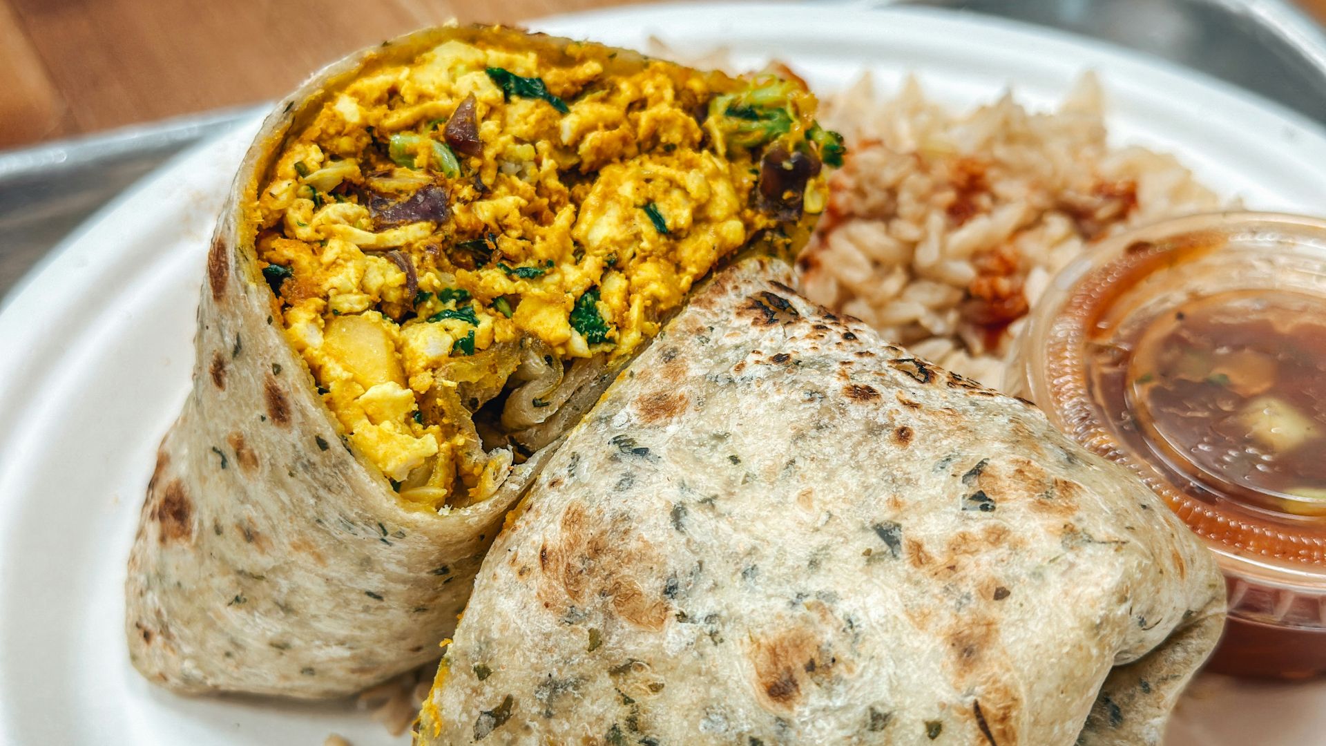 a white plate topped with a burrito and rice