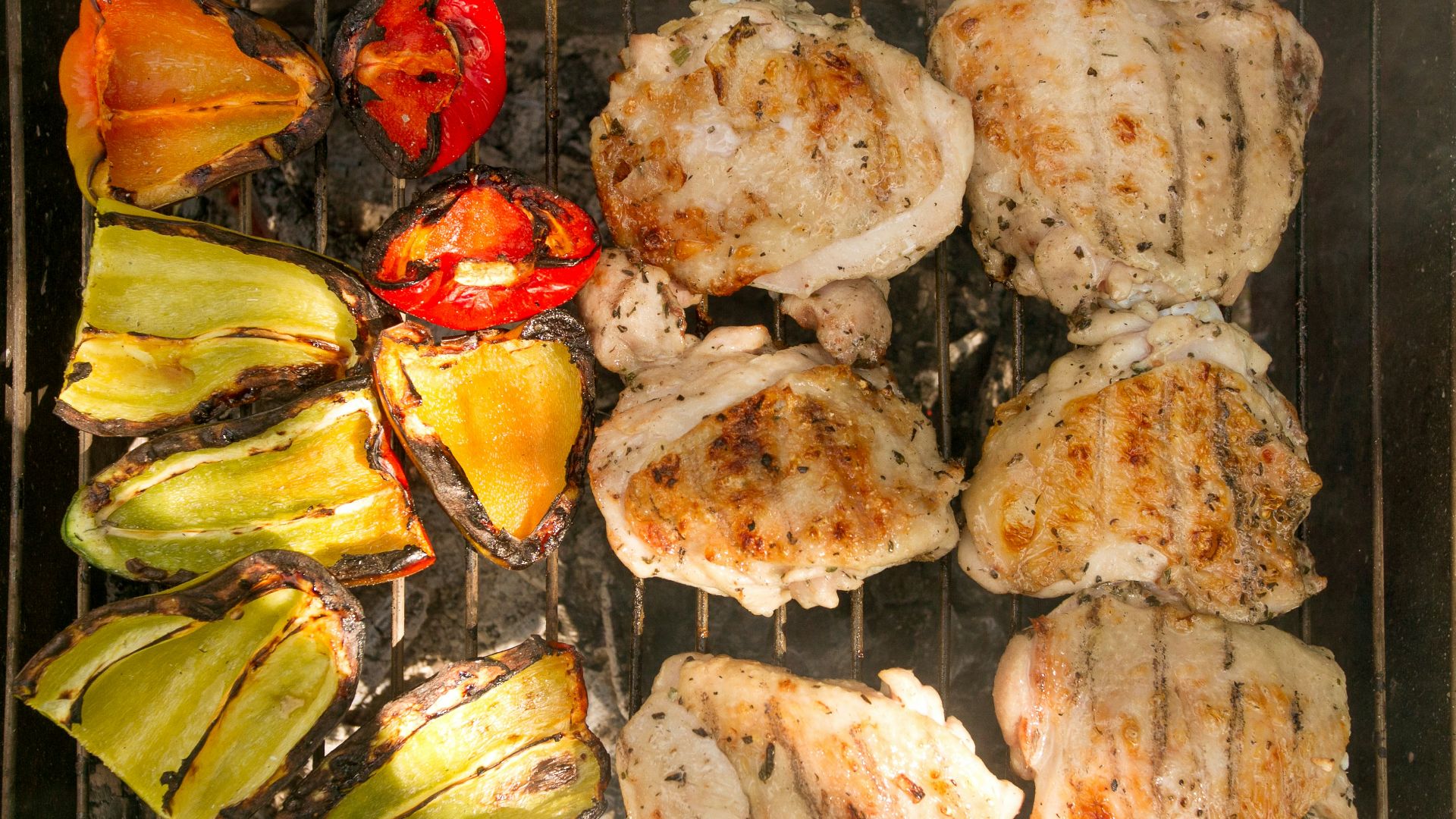 a grill with chicken and vegetables cooking on it