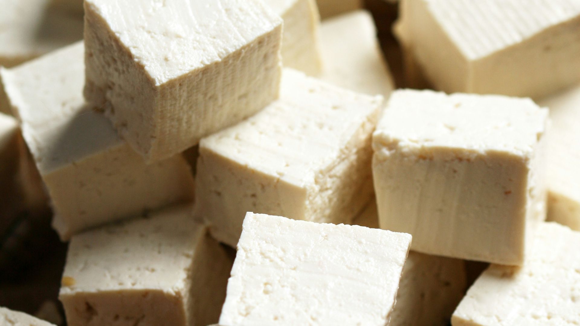 A pile of tofu cubes sitting on top of a cutting board
