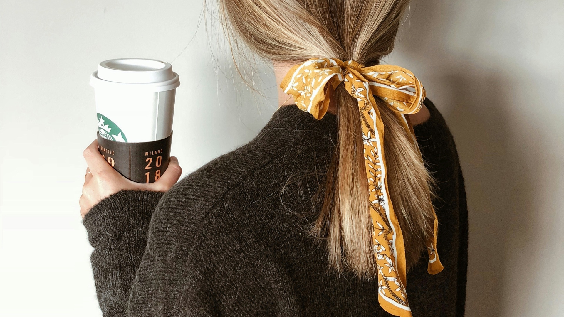 woman in black sweater holding starbucks coffee cup