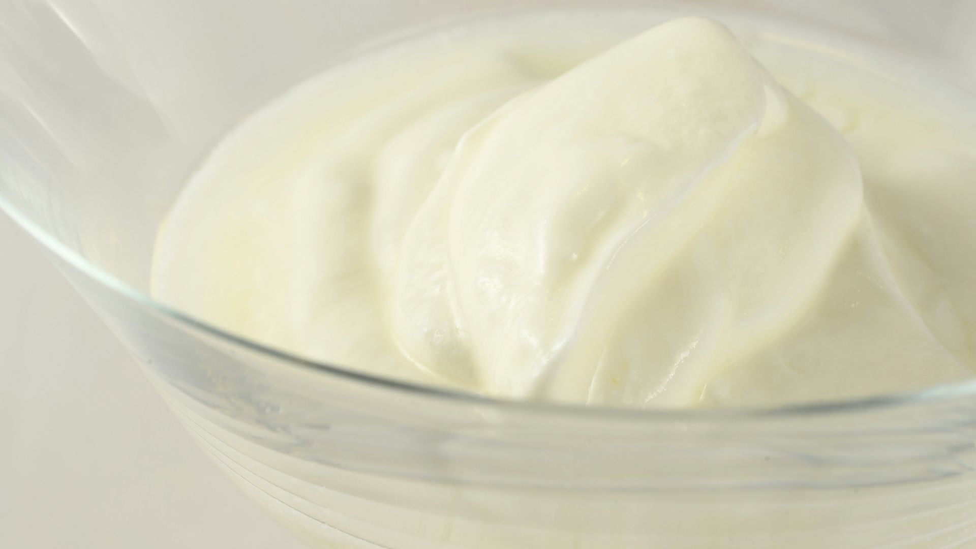 a glass bowl filled with cream on top of a table