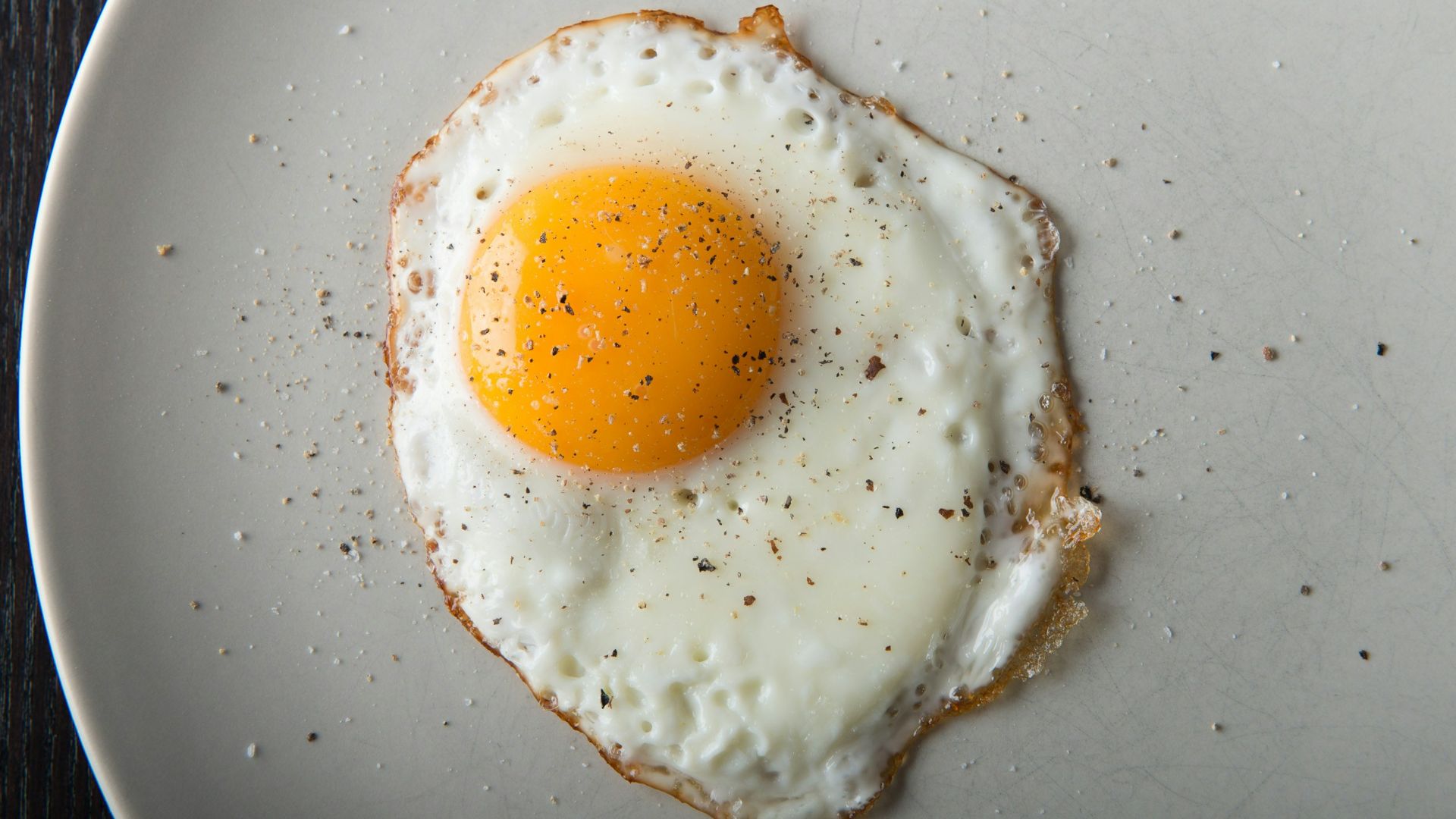 a fried egg on a white plate on a wooden table