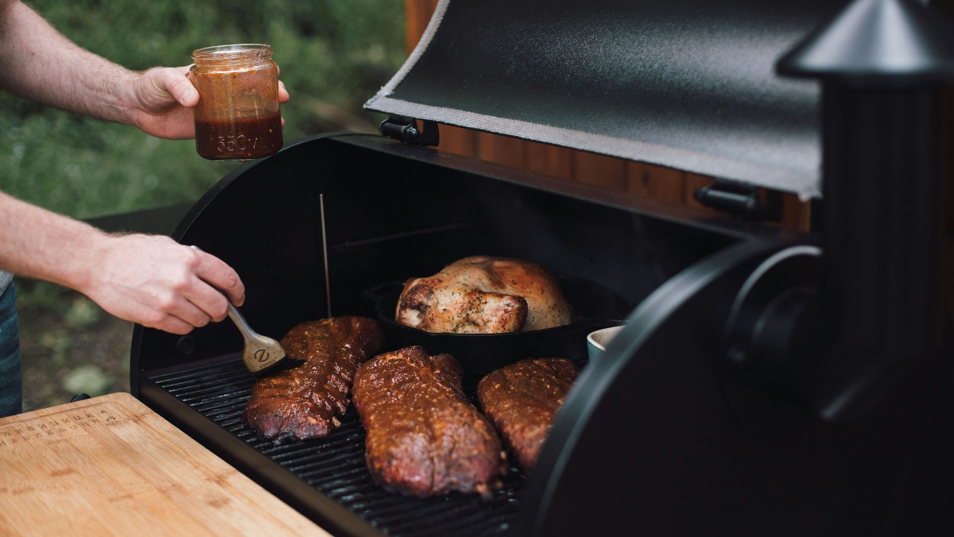 person holding knife slicing meat on black grill