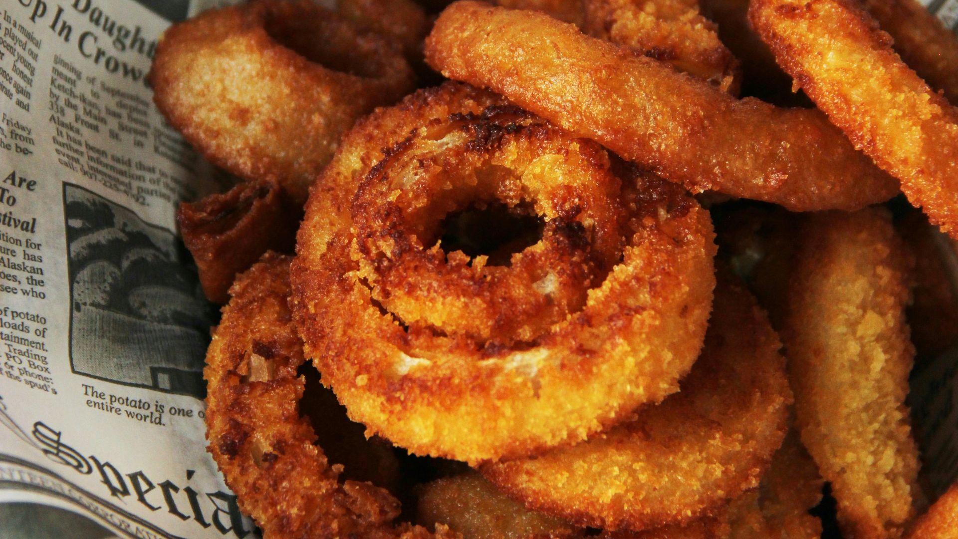 a pile of fried onion rings sitting on top of a newspaper
