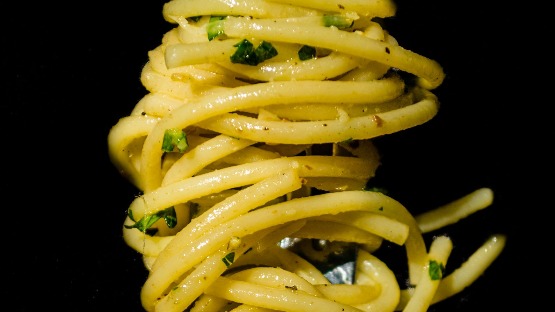 pasta with green sauce on black background