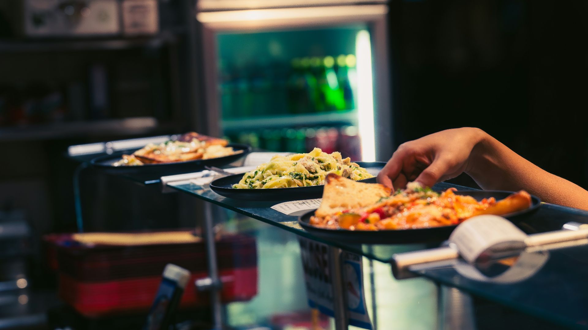 Hand reaching for a slice of pizza