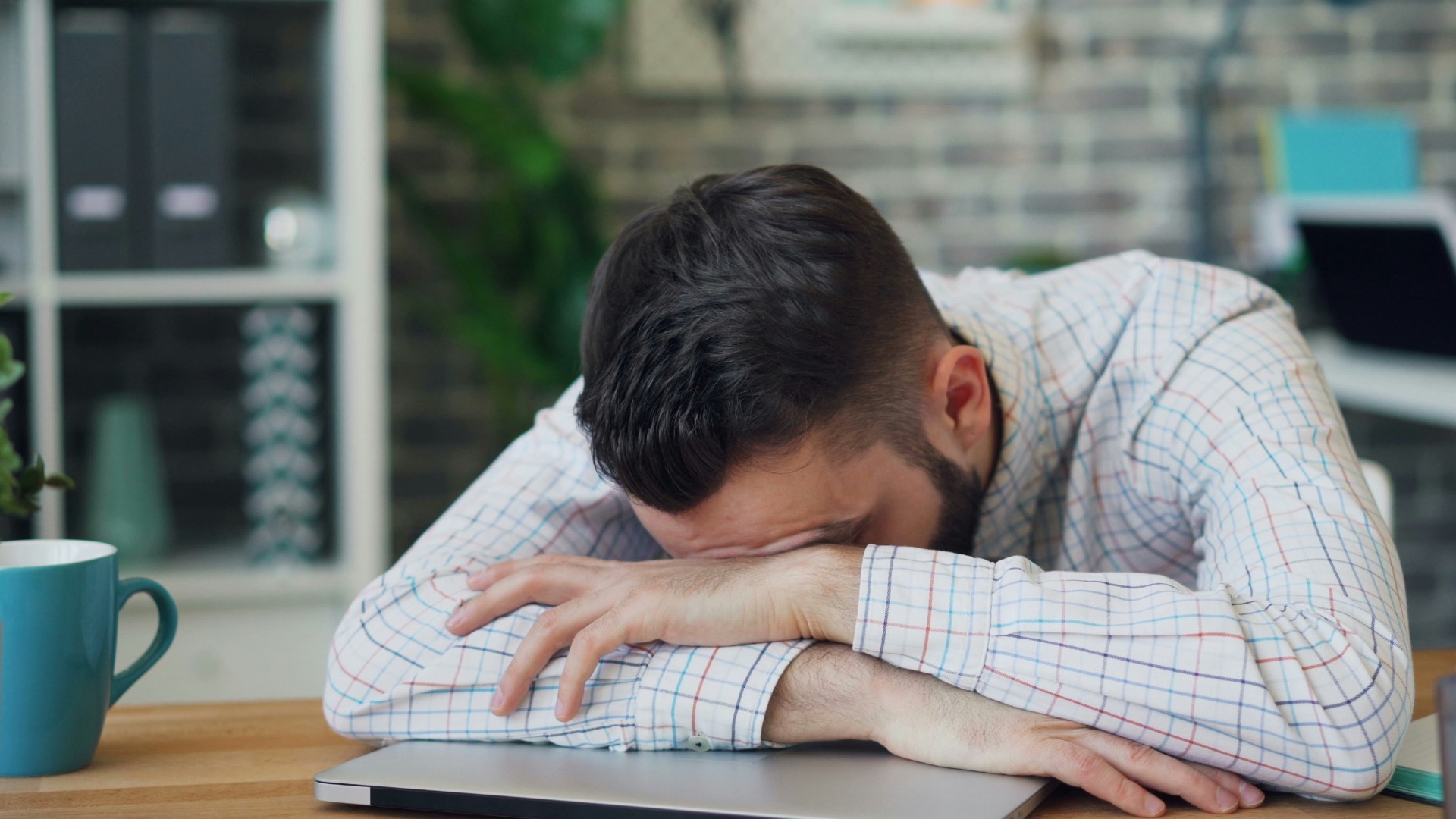 a man sitting at a desk with his head in his hands