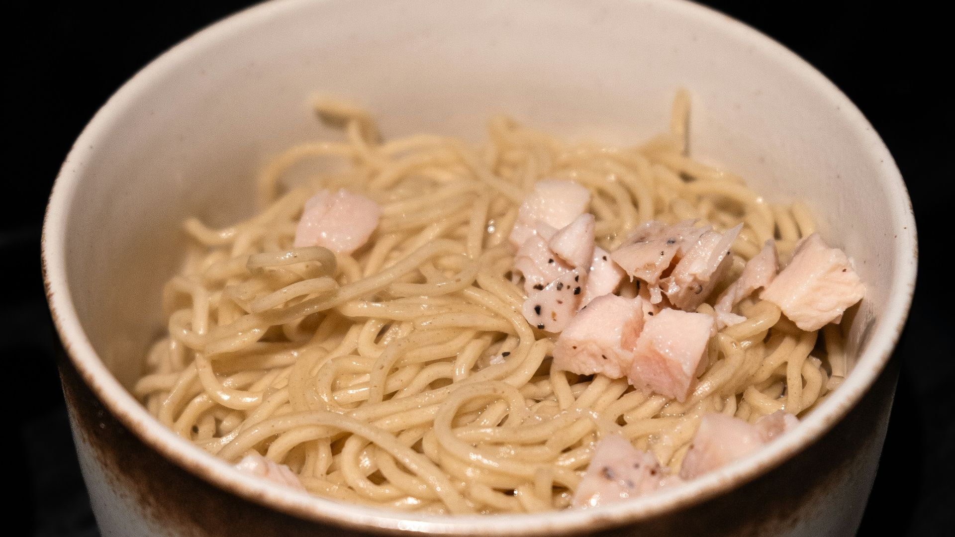 a white bowl filled with noodles and meat