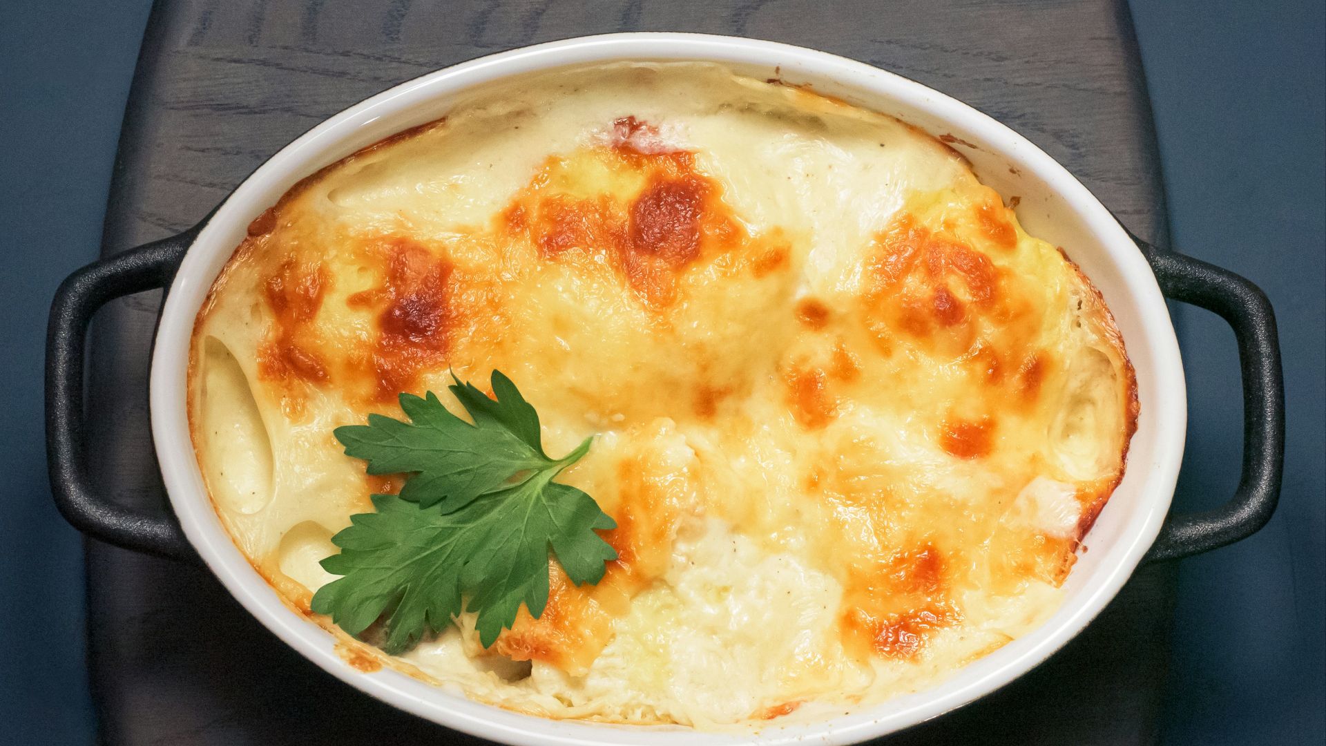 a casserole dish with cheese and parsley