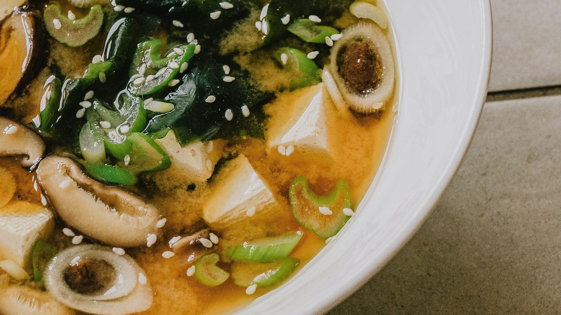 a white bowl filled with soup on top of a tiled floor