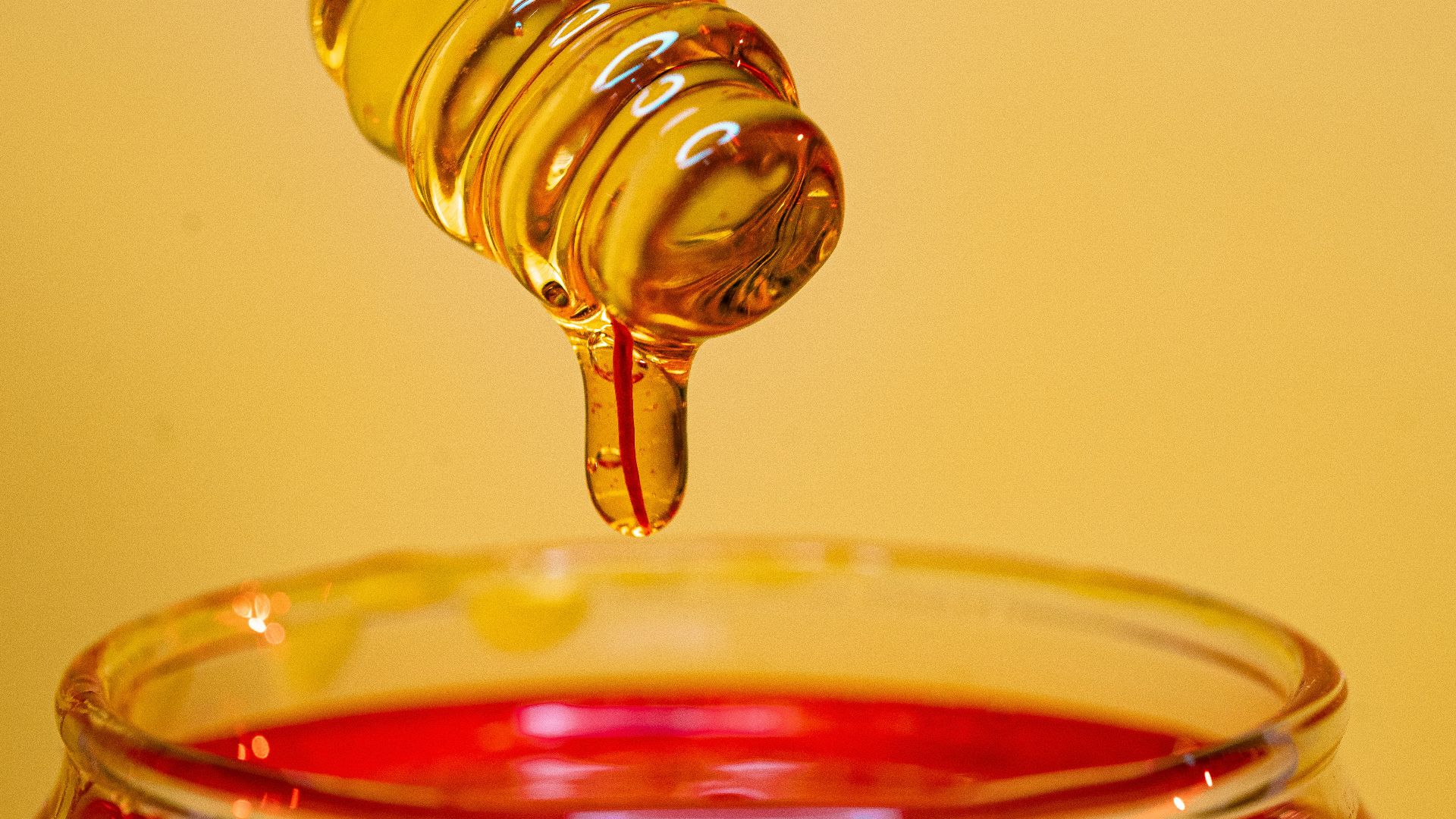 clear glass bottle pouring red liquid on clear drinking glass