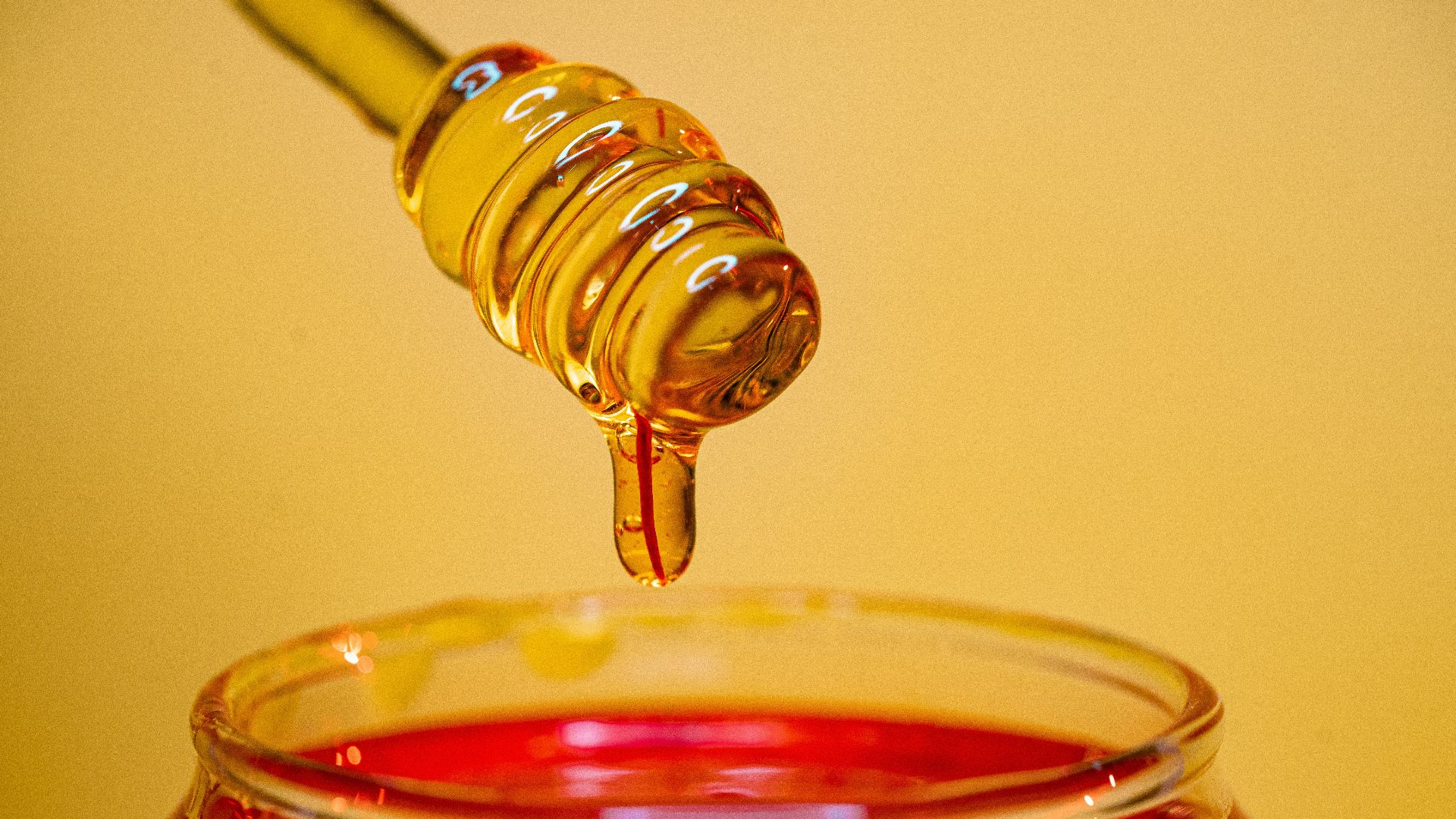 clear glass bottle pouring red liquid on clear drinking glass