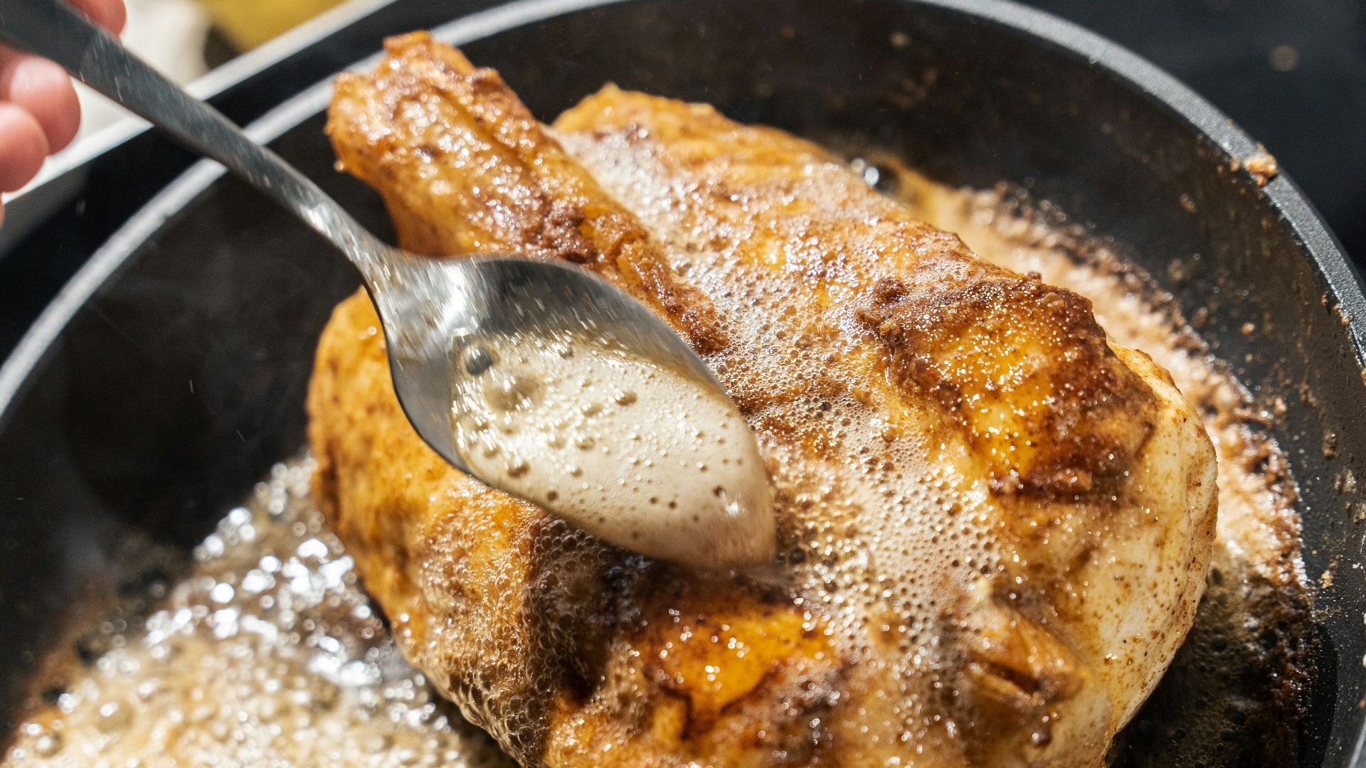 Basting chicken in a hot pan with butter