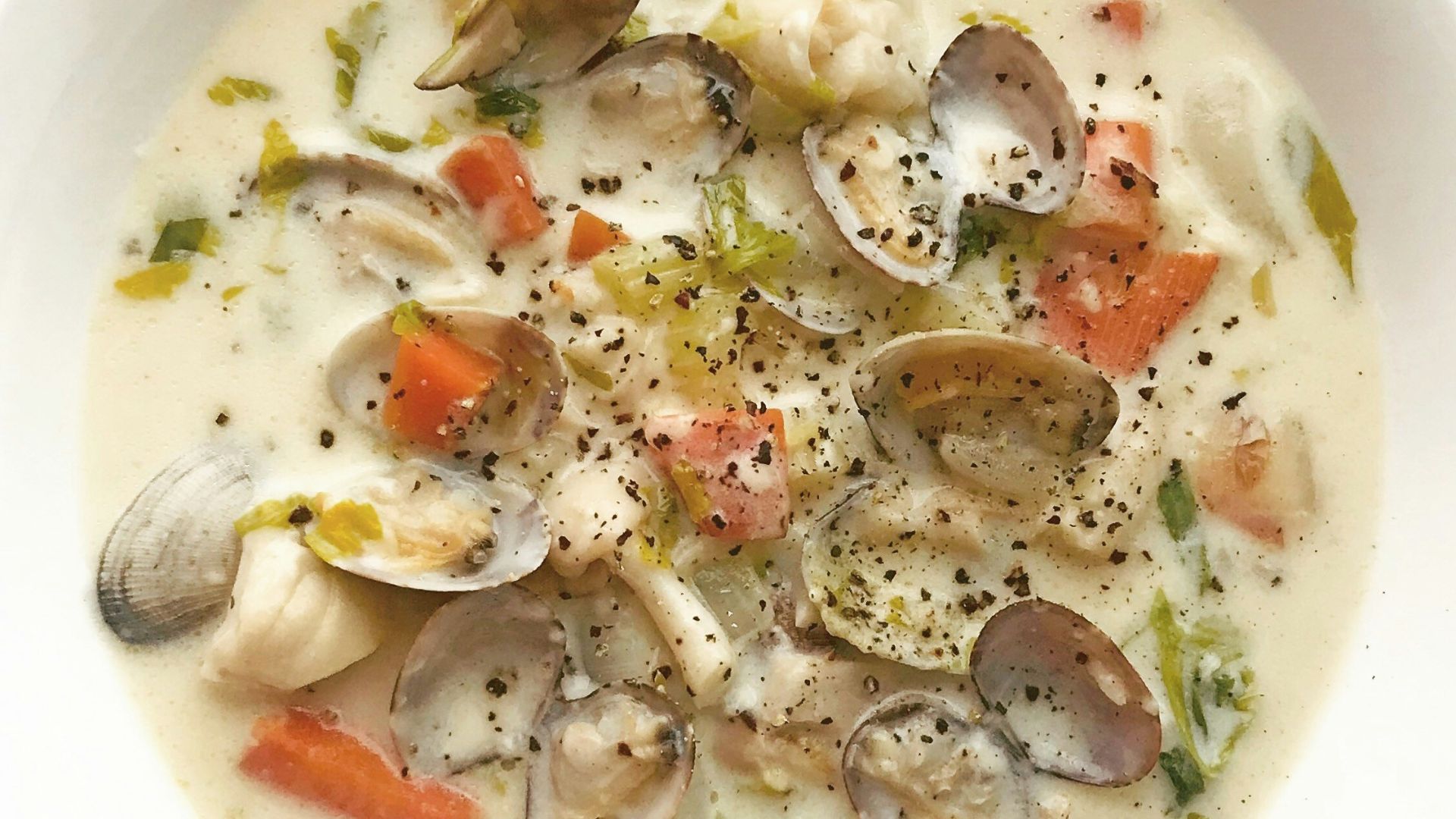 clam and vegetable soup in white ceramic bowl
