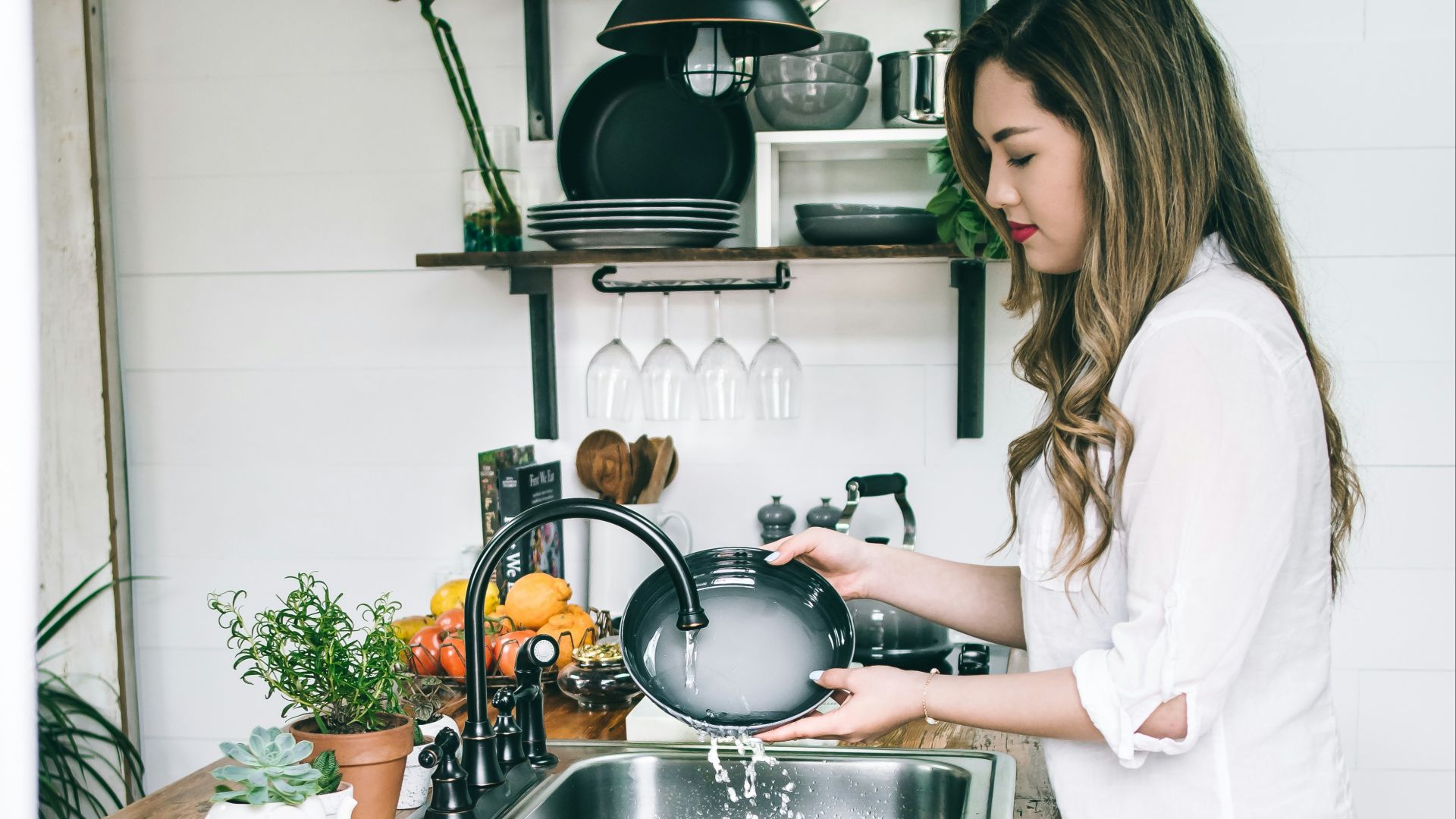 woman wearing white blouse washing dish on the faucet