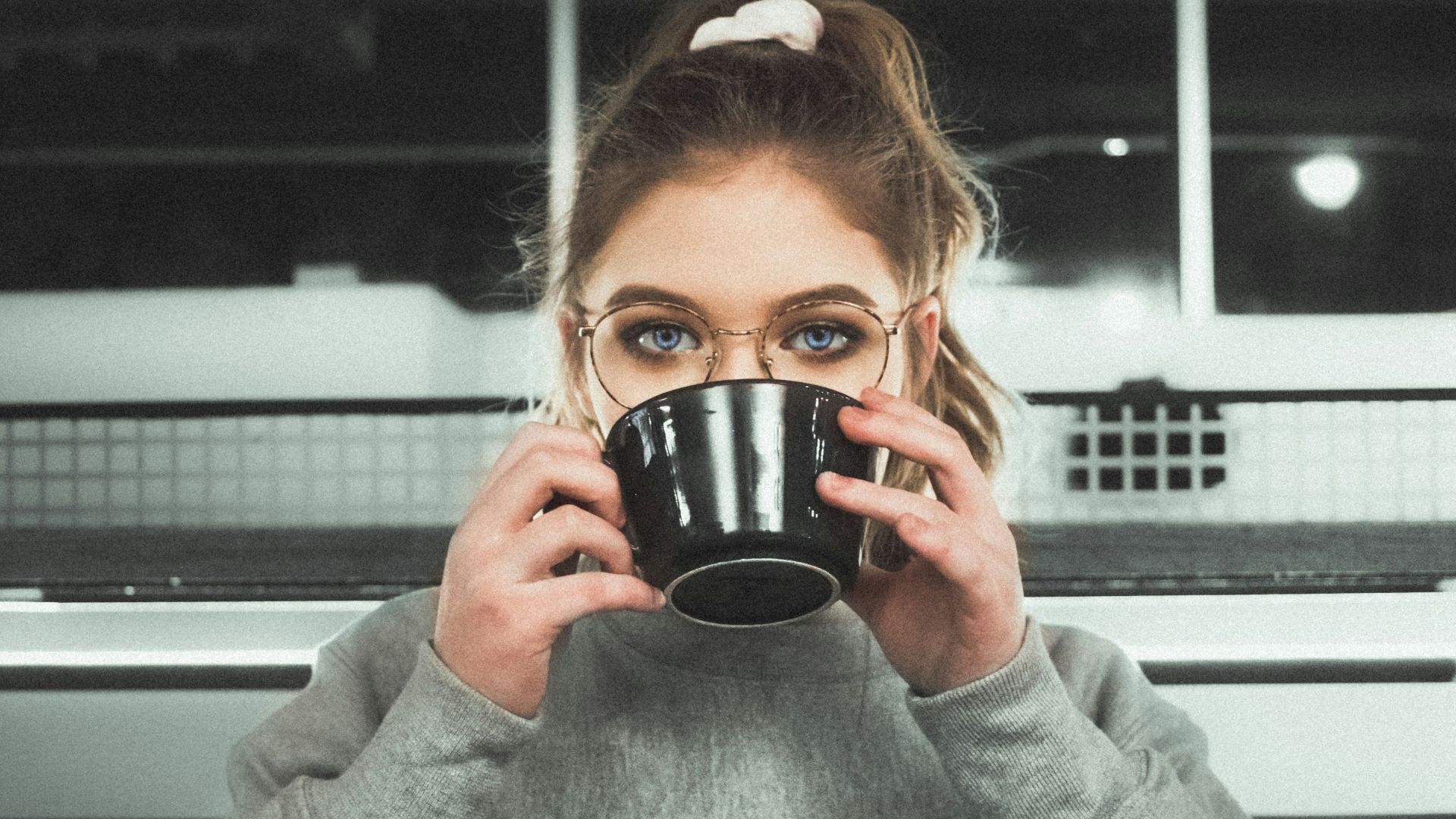 woman wearing glasses holding black ceramic mug