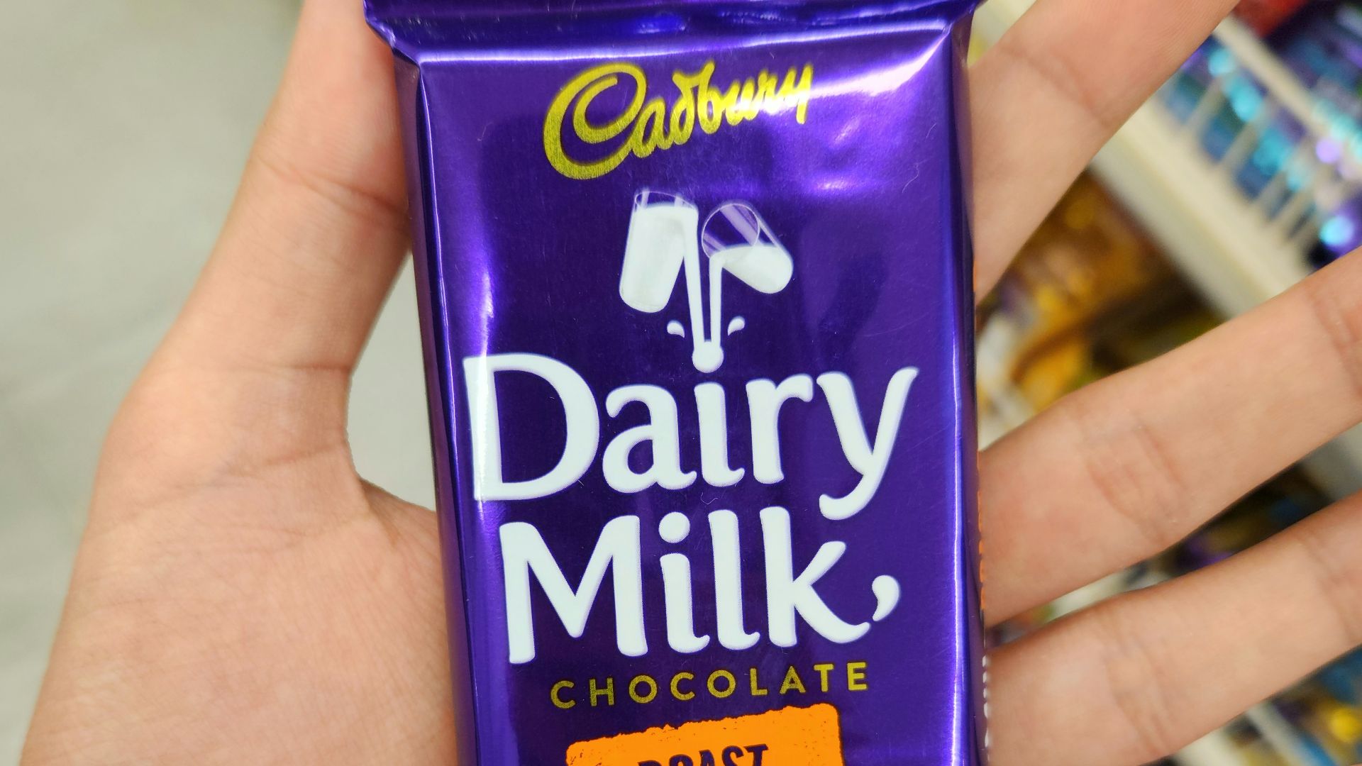 A hand holds a cadbury dairy milk chocolate bar.