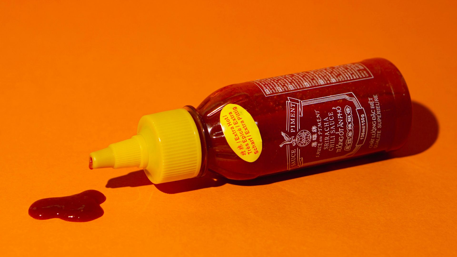 a bottle of ketchup sitting on an orange surface