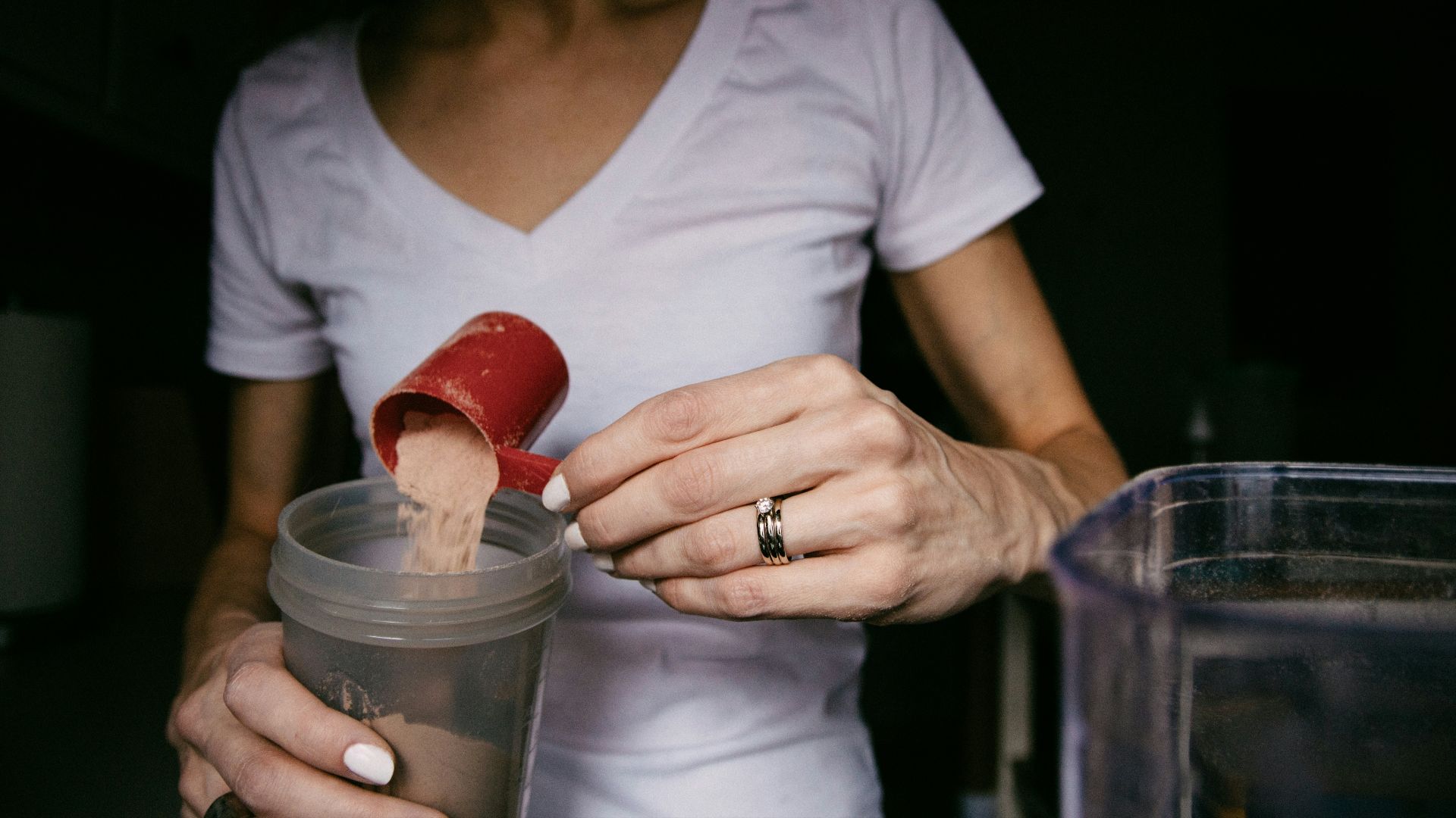 woman in white v neck shirt holding red heart shaped lollipop