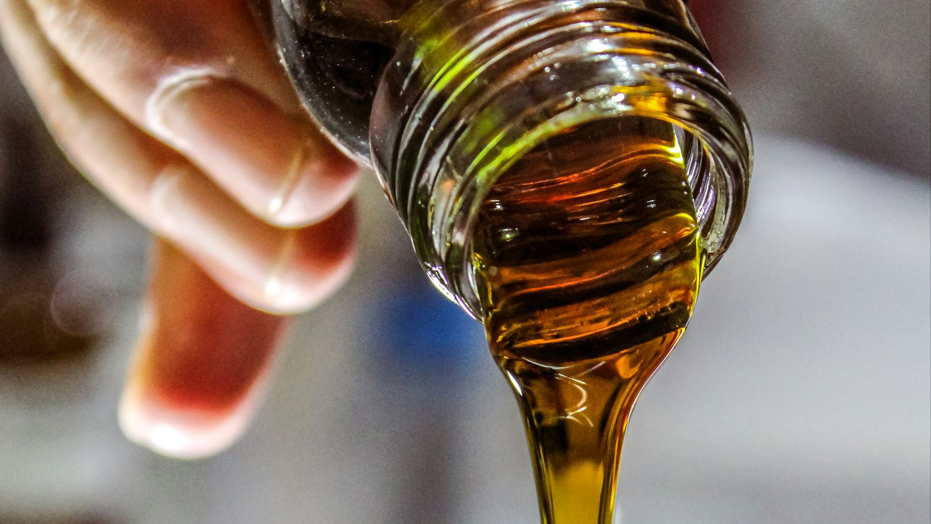 person holding clear drinking glass with brown liquid