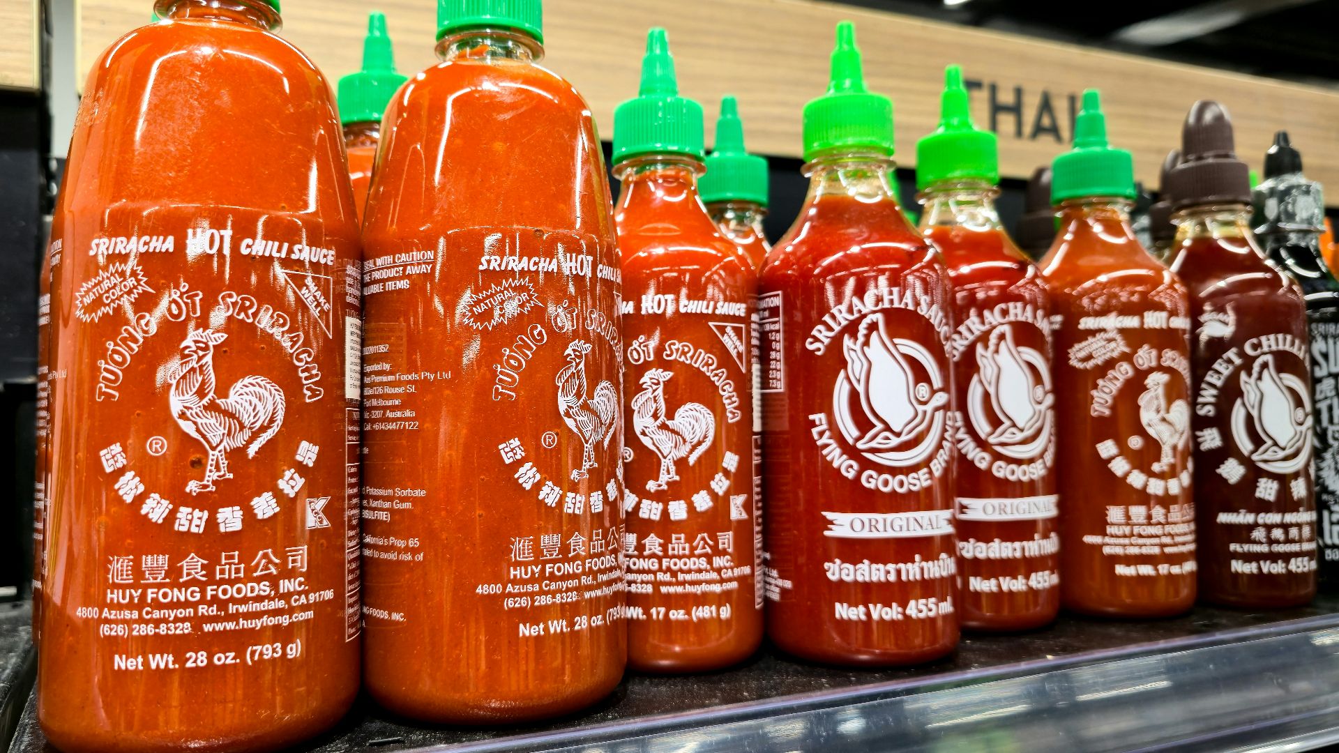 Rows of sriracha hot sauce bottles on a shelf.