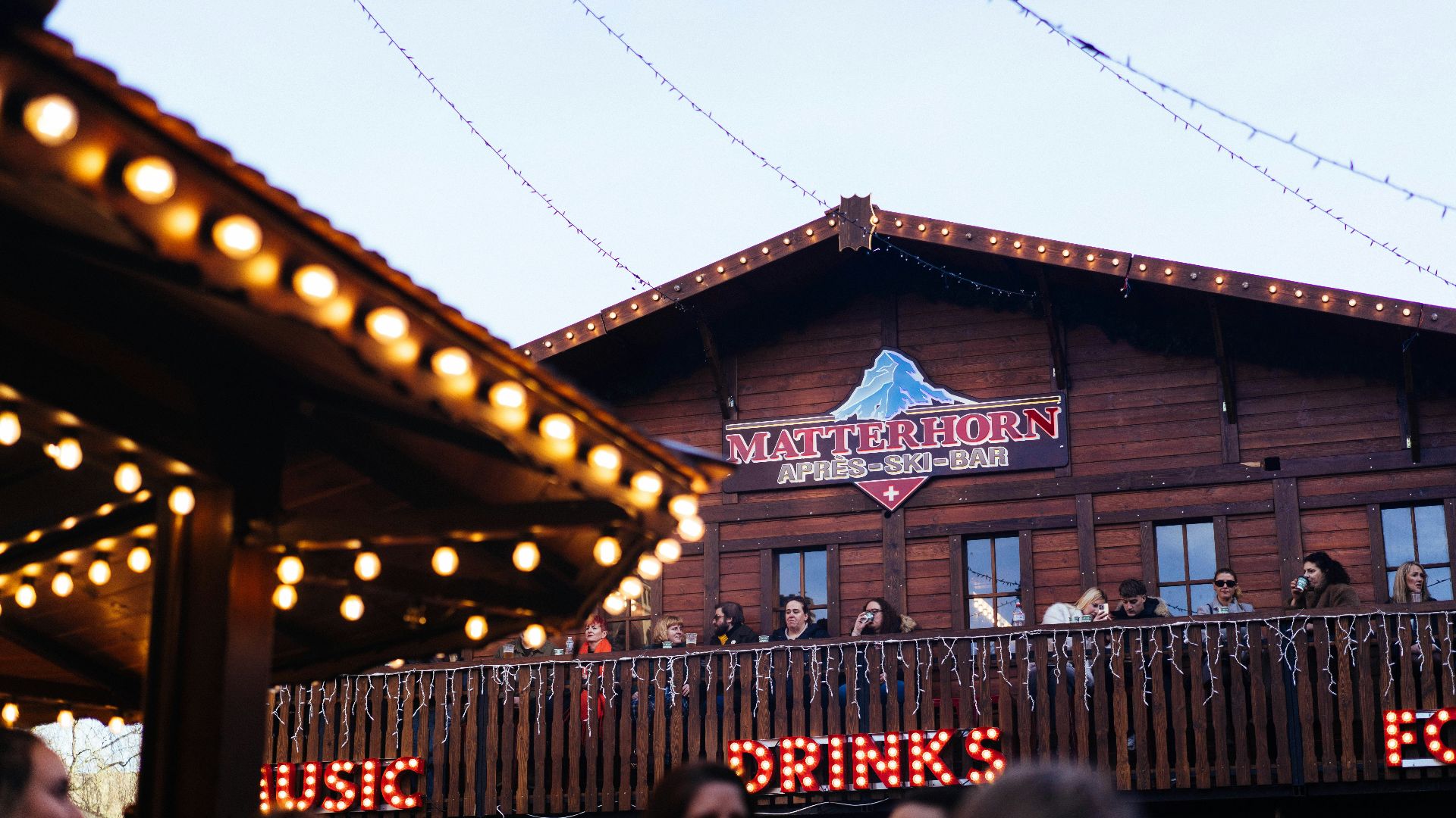 Wooden building with lights and people on balcony