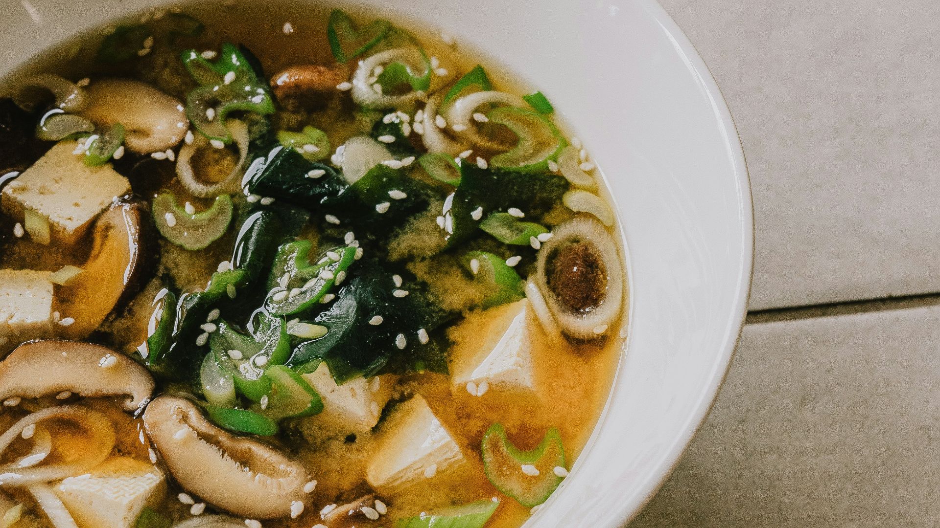 a white bowl filled with soup on top of a tiled floor