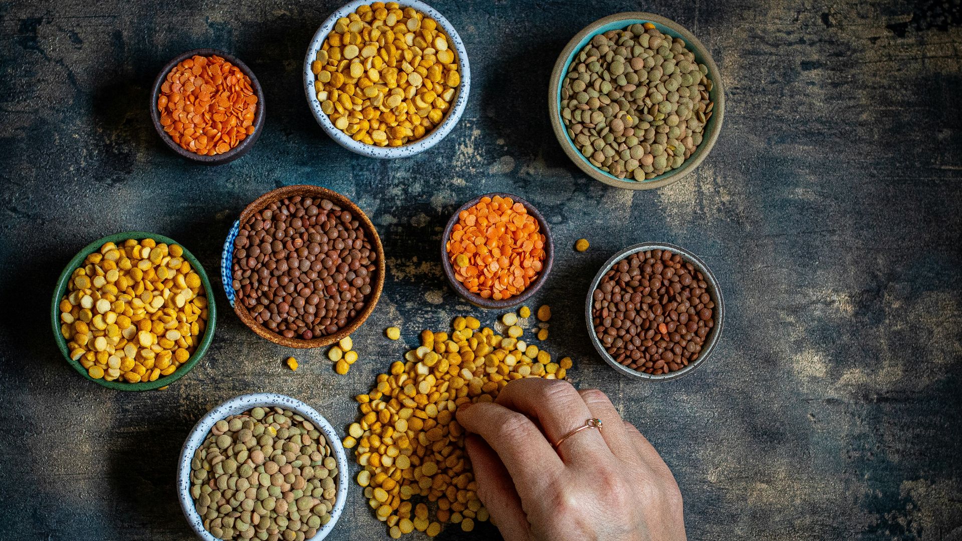 a person touching a bowl of lentils on a table
